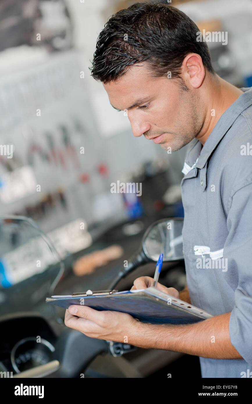 Mechanic writing on his clipboard Stock Photo - Alamy