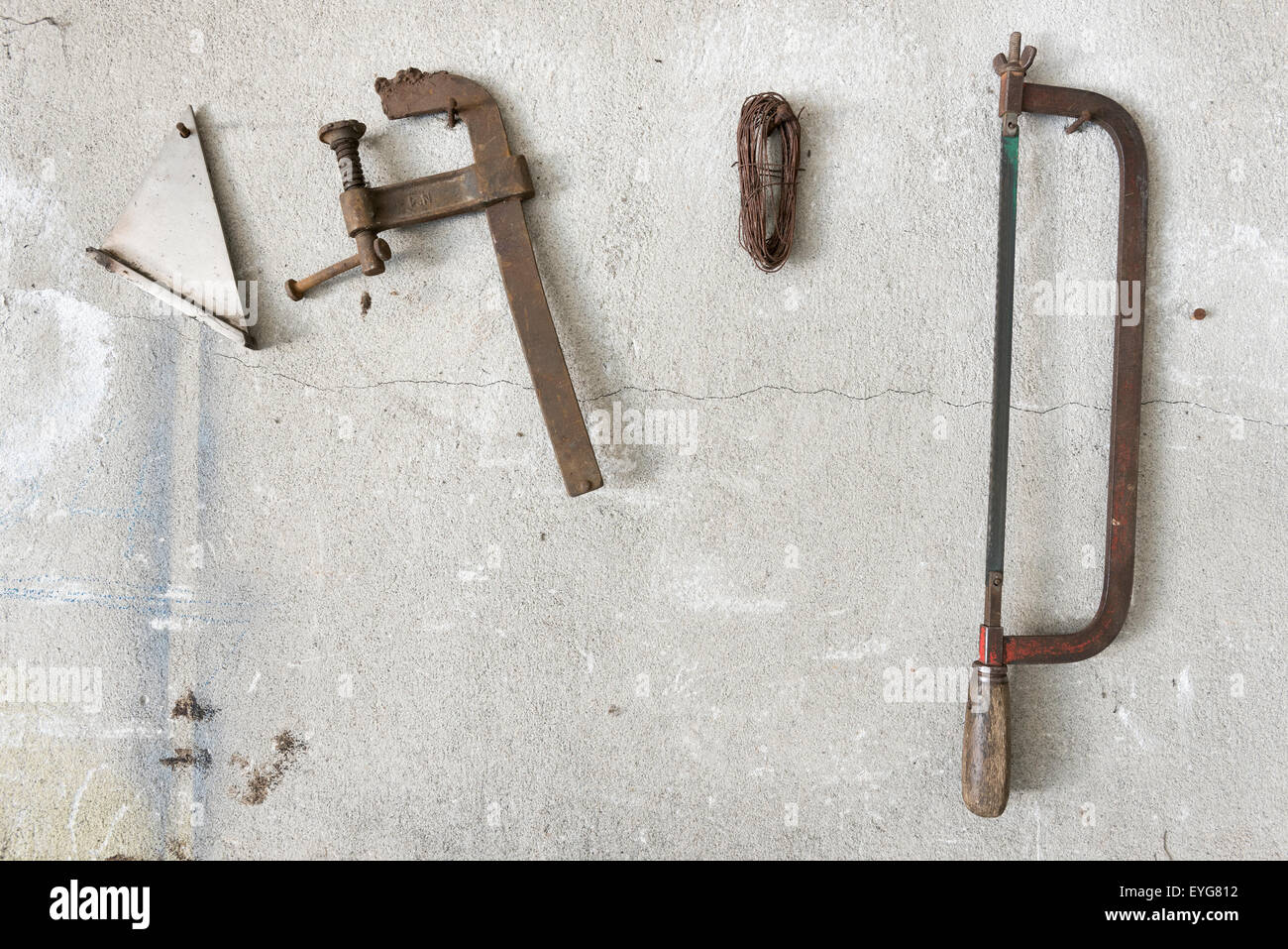 old hacksaw and clamp  hanging on garage wall Stock Photo