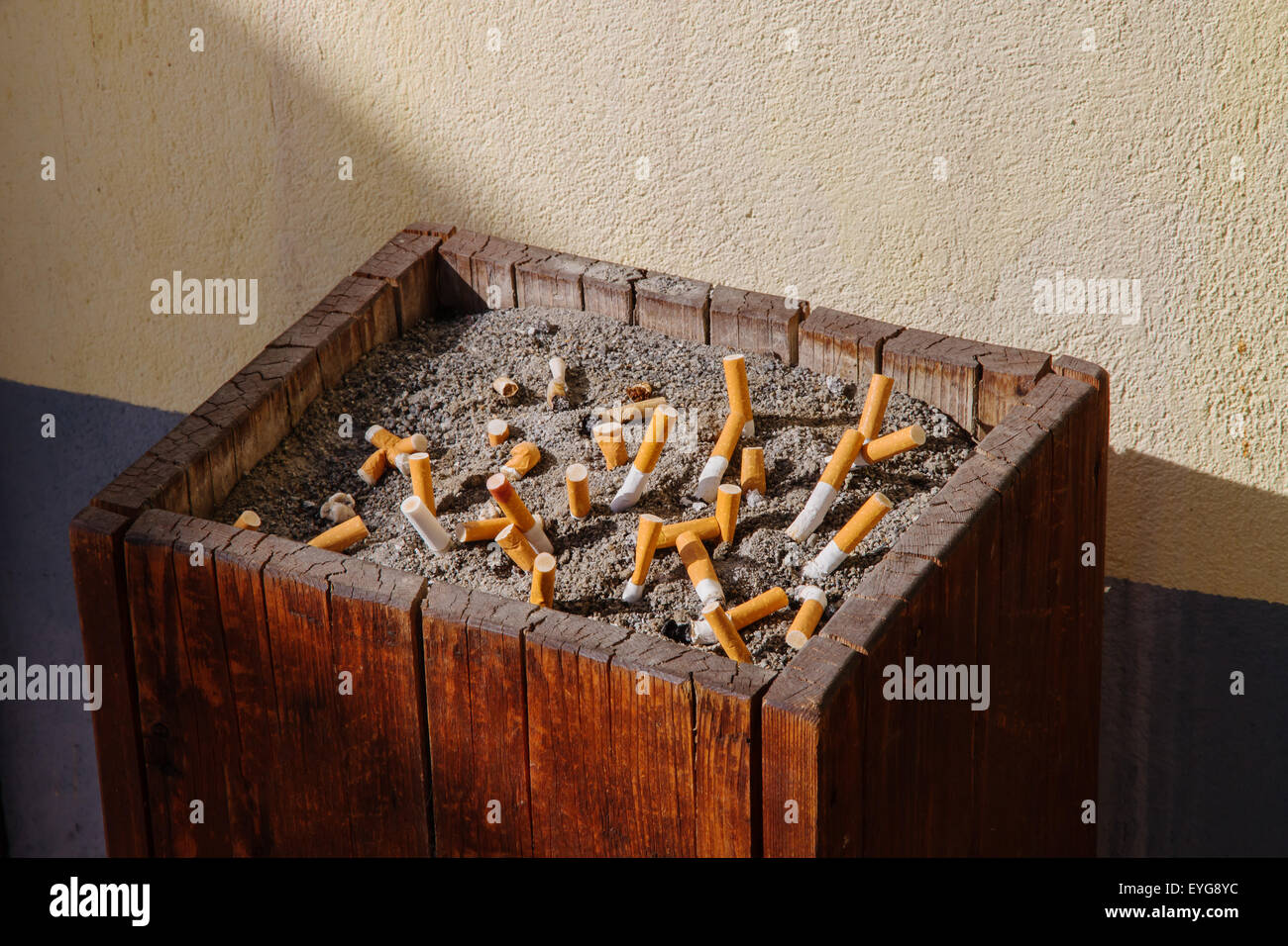 wooden ashtray with sand full of smoked cigarettes symbol of smoking