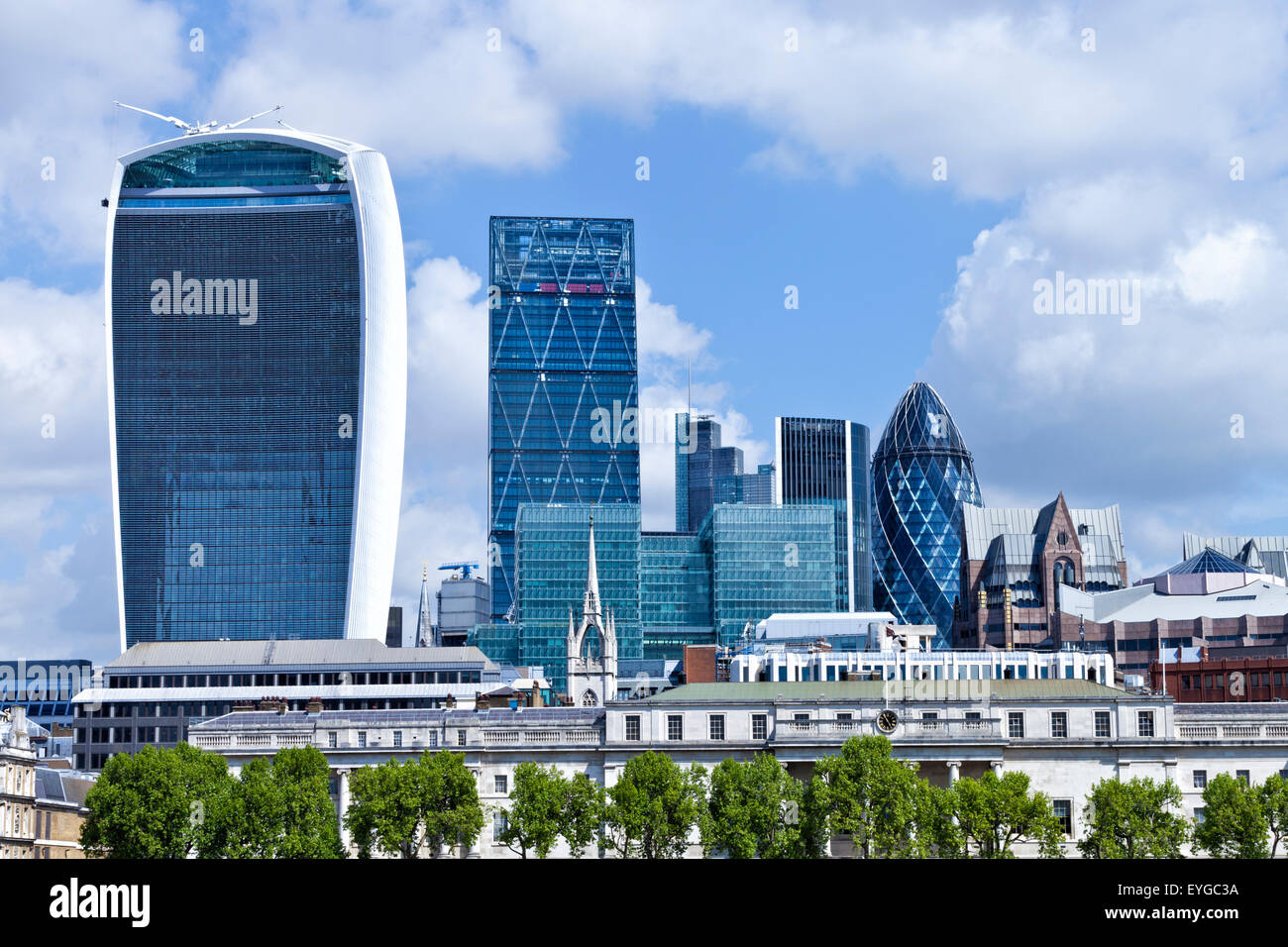 Cityscape of London banking and insurance district landmark buildings on a summer sunny day with green trees in foreground Stock Photo