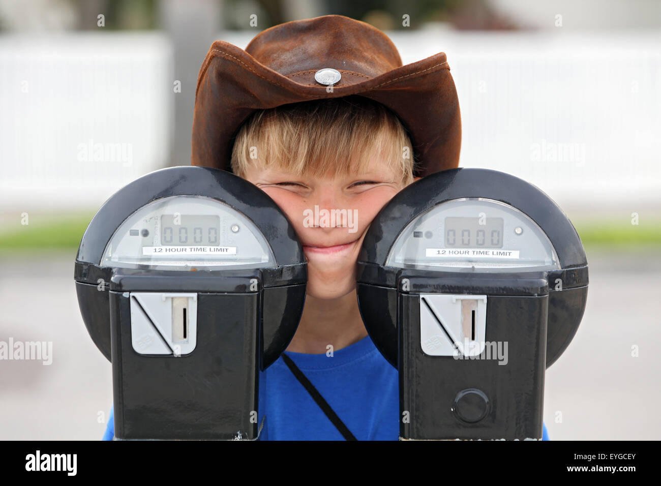 Saint Petersburg, Florida, boy with cowboy hat looking out from behind two parking meters Stock Photo