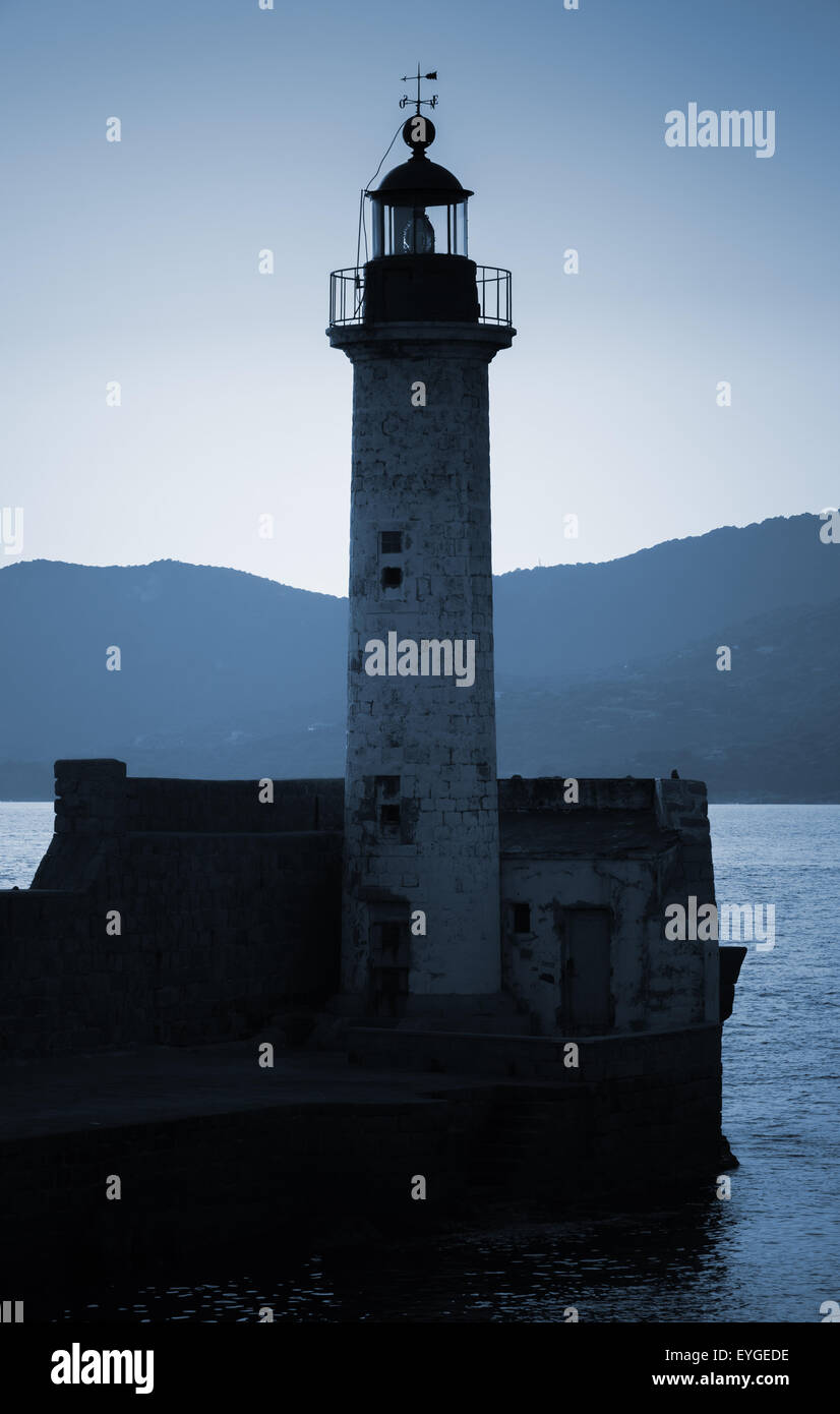 Old lighthouse tower silhouette on the coast of Mediterranean Sea, no light. Blue toned, stylized night photo Stock Photo