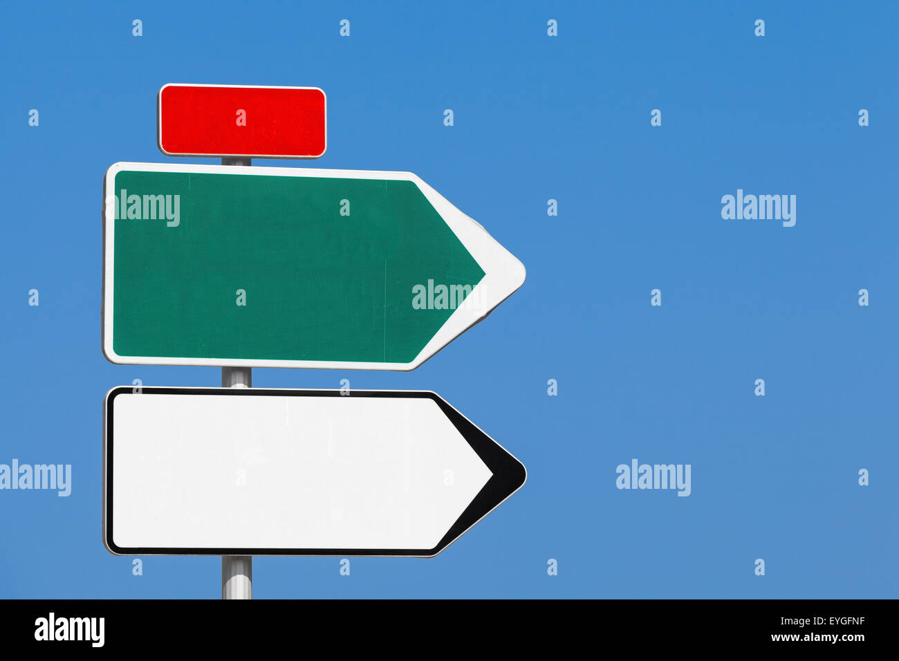 Road sign. Blank white and green arrows for destination cities names and red label for road number over clear blue sky backgroun Stock Photo