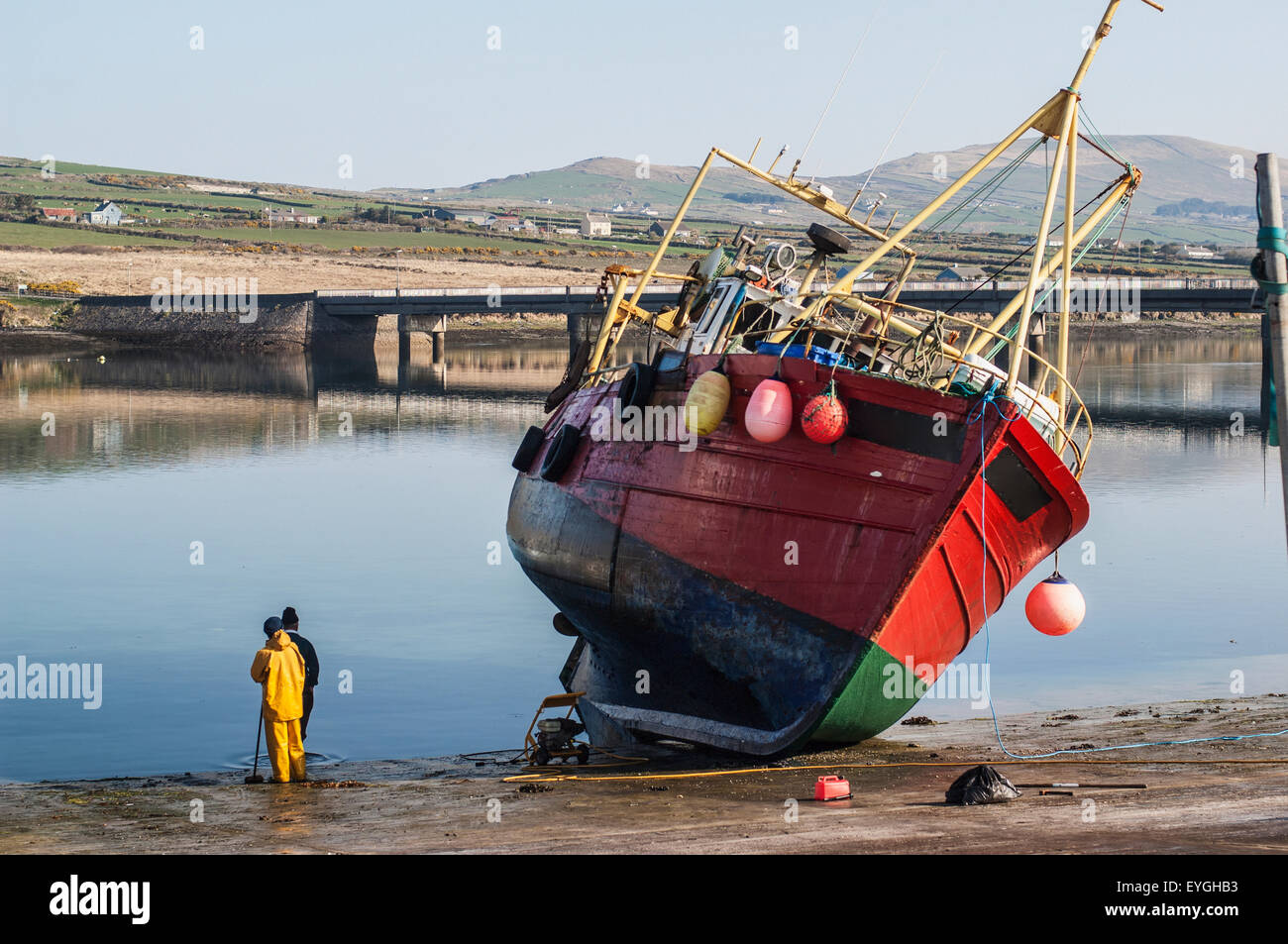 Sea fisherman in yellow waterproof overalls, standing by his fishing boat  and looking out to sea Stock Photo - Alamy