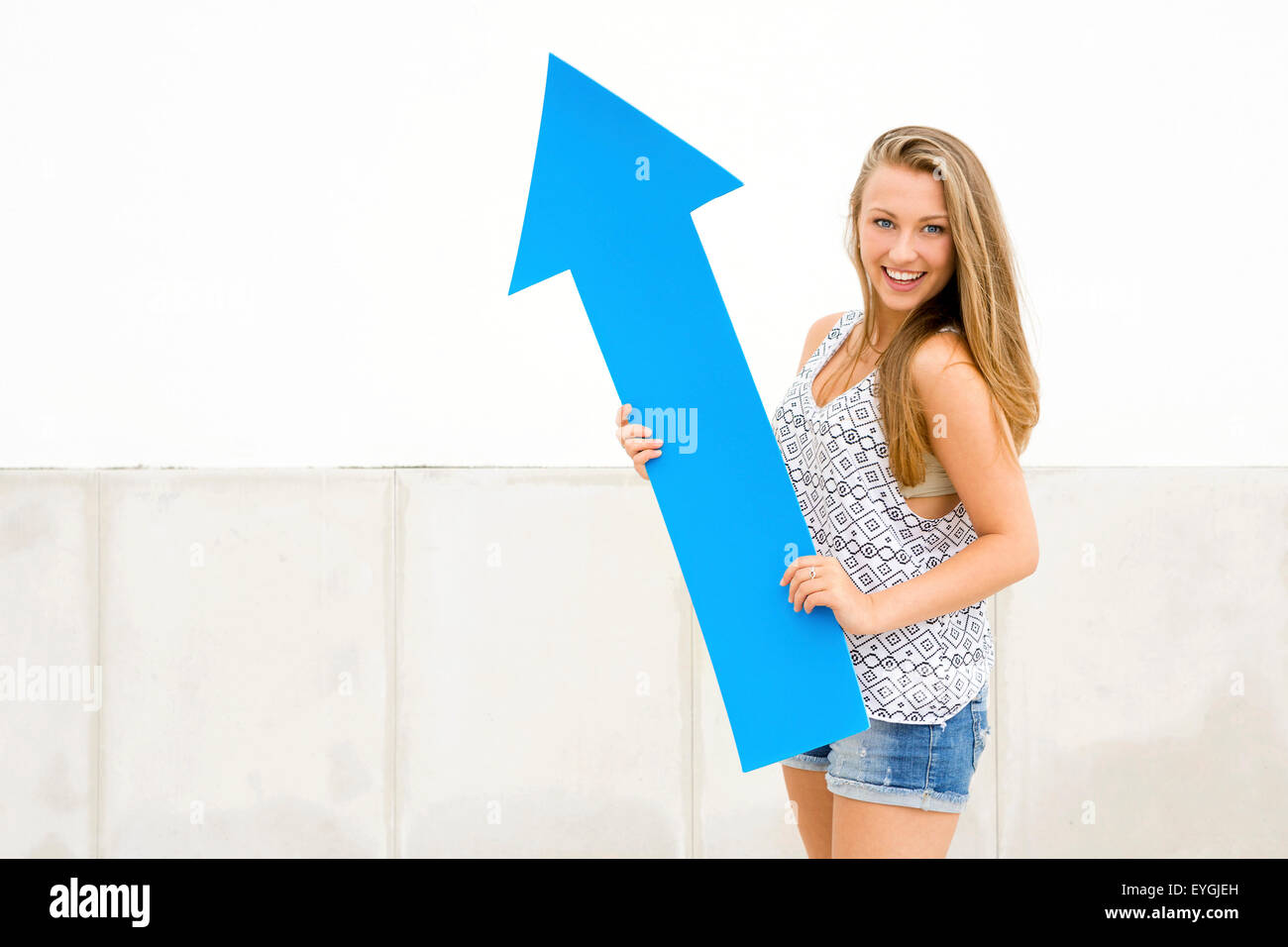 Young and beautiful girl holding a blue arrow Stock Photo - Alamy