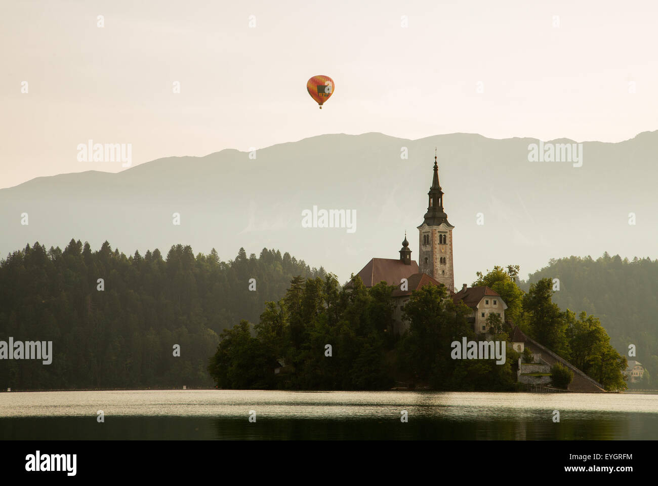 A hot air balloon rising over the mountains behind Lake Bled’s island