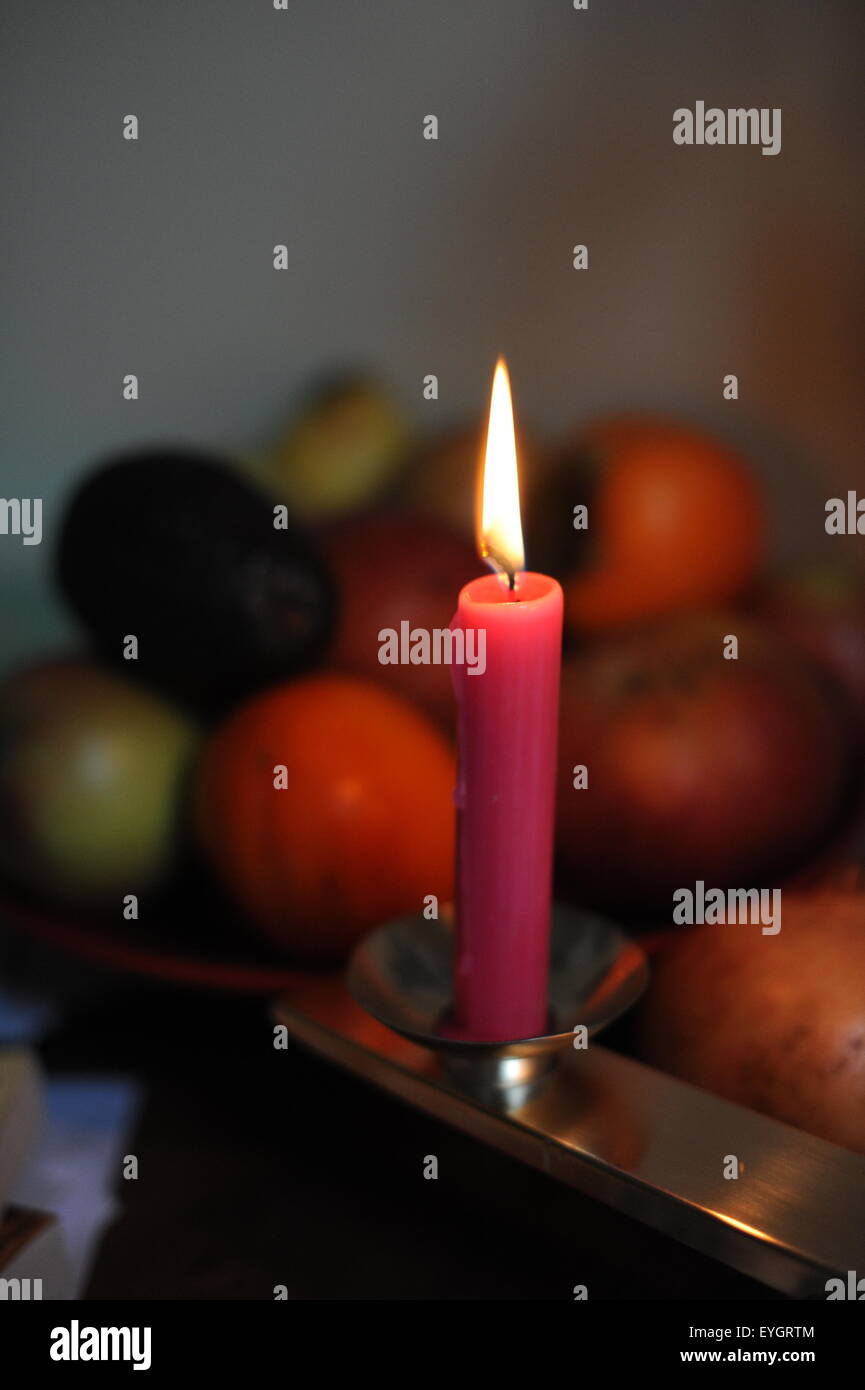 Pink candle burning in front of fruits Stock Photo Alamy