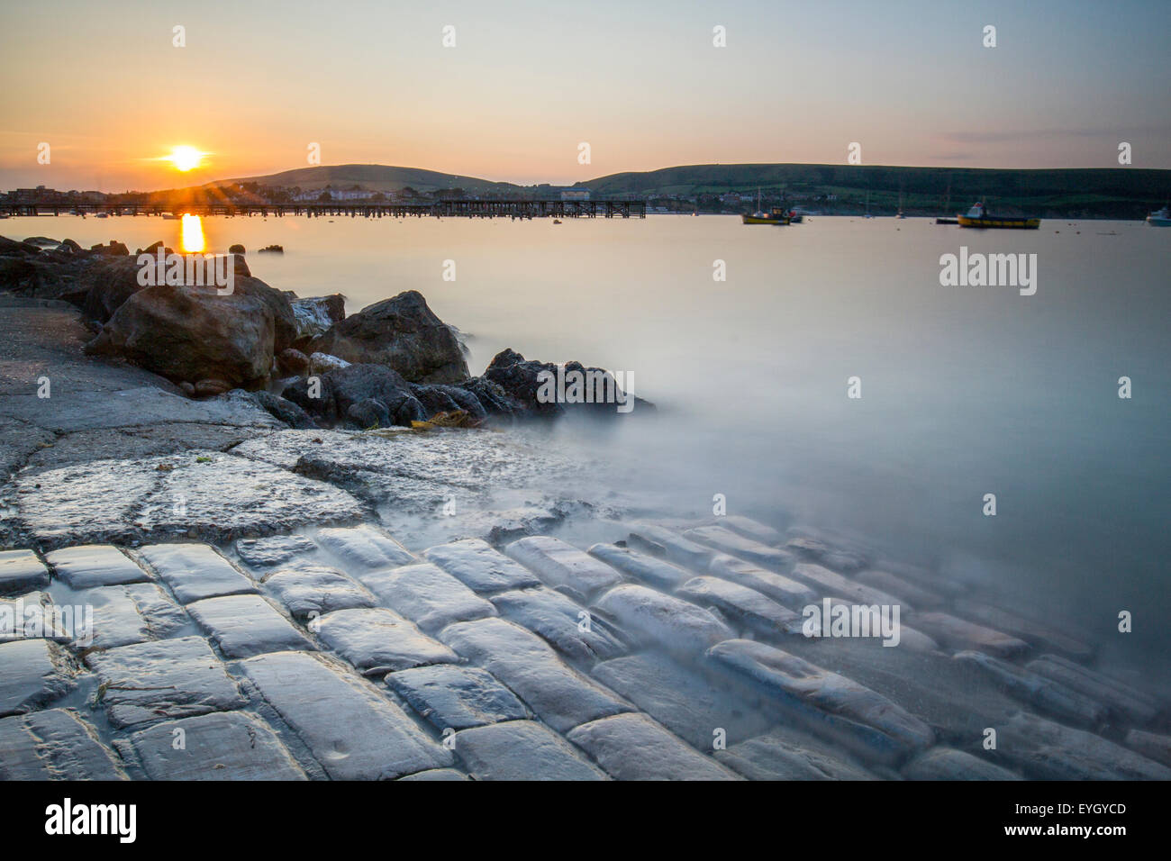 long exposure of misty water on cobbled boat ramp in Swanage Bay at sunset Stock Photo