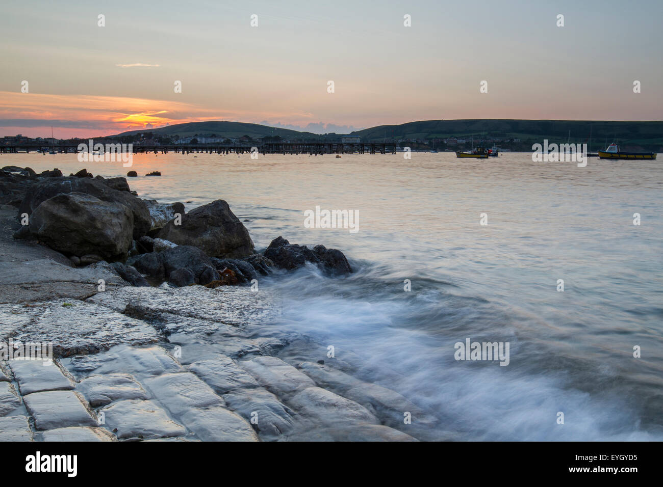 waves crashing on cobbled boat ramp at sunset in Swanage bay Stock Photo