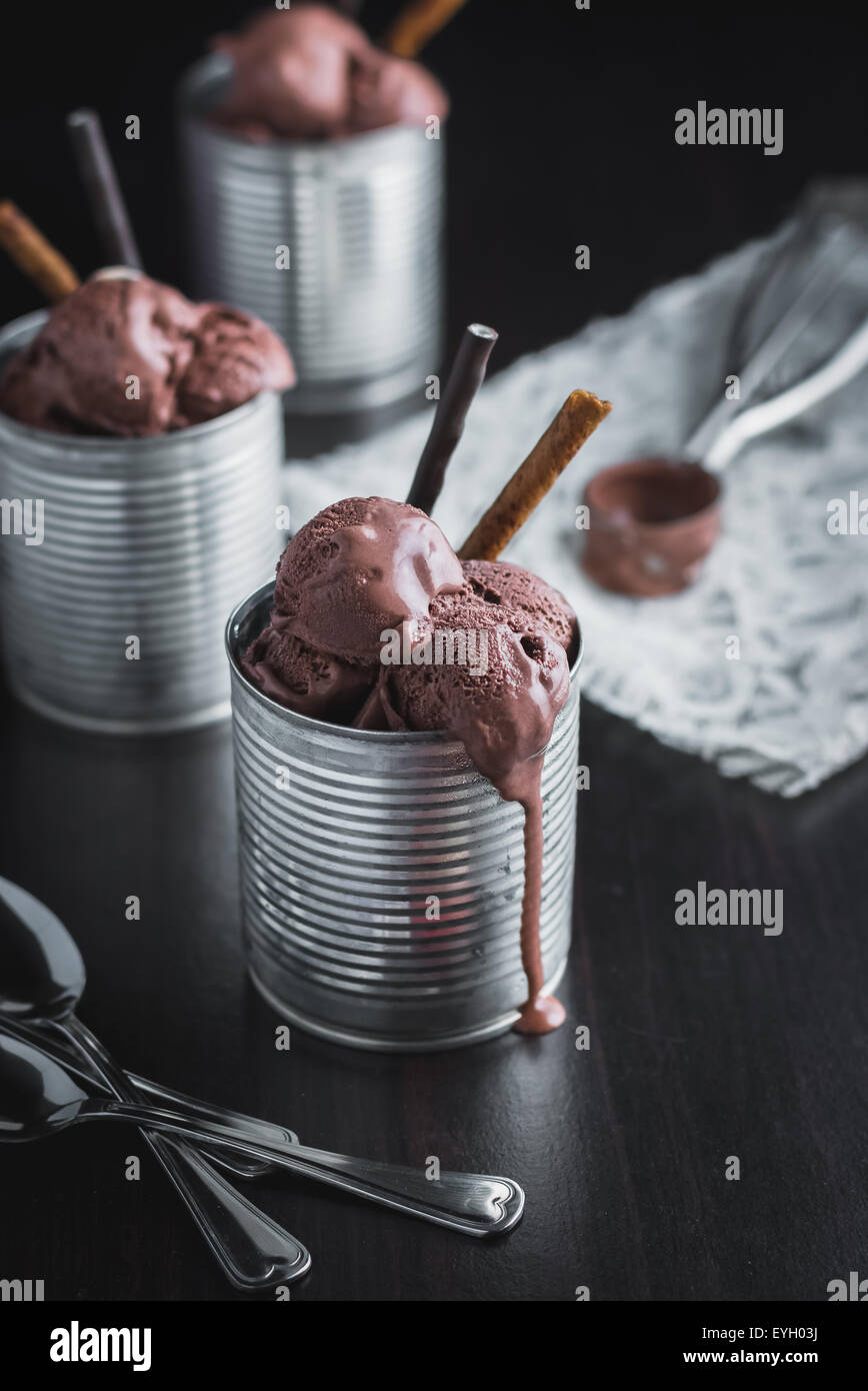 Chocolate ice cream in metal containers on black wood background Stock Photo