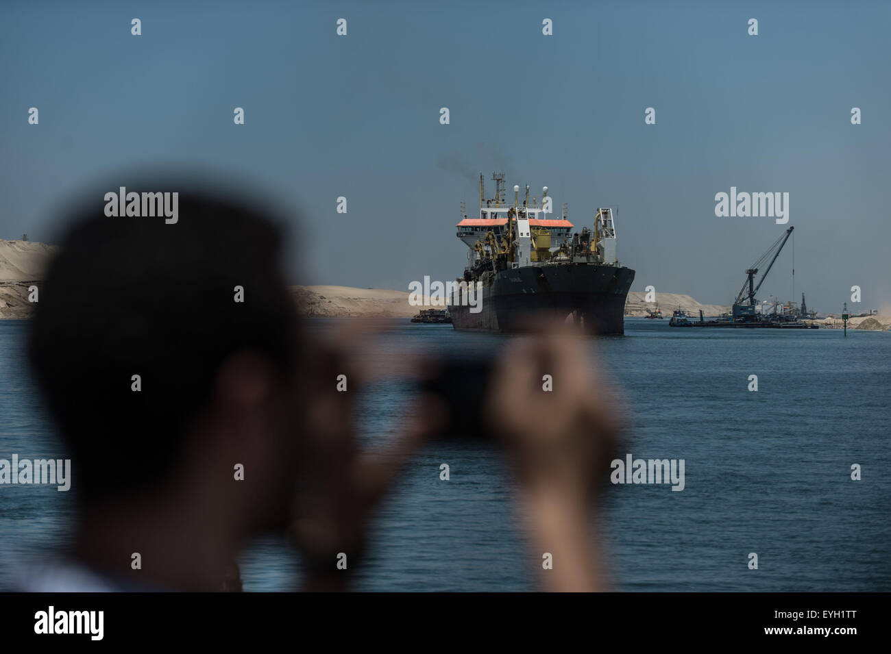 Ismailia, Egypt. 29th July, 2015. A man takes photos on the new Suez Canal in Ismailia, a port city in Egypt, on July 29, 2015. The dredging work of Egypt's 'New Suez Canal' has been completed and the waterway is ready as well as safe for huge ship navigation, Mohab Memish, head of the Suez Canal Authority (SCA), told reporters in a press conference Wednesday. © Pan Chaoyue/Xinhua/Alamy Live News Stock Photo