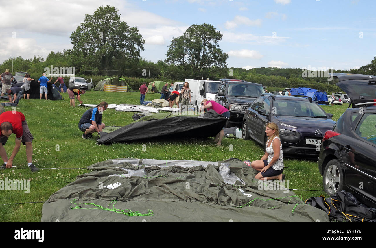 Random people on camp site struggling putting up tents in a field Stock Photo