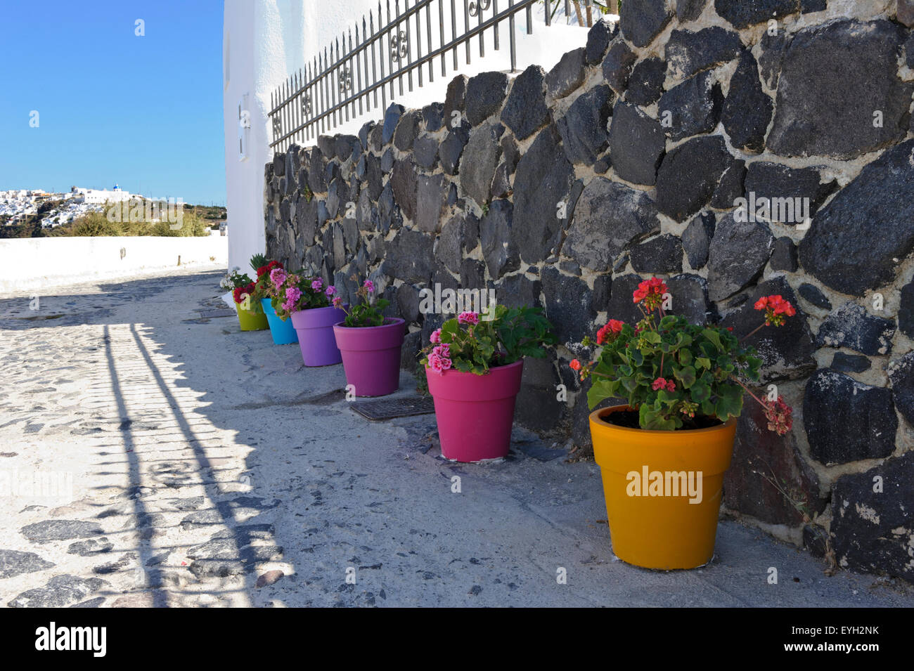 A row of colourful potted plants by a stony wall, Santorini, Greece. Stock Photo