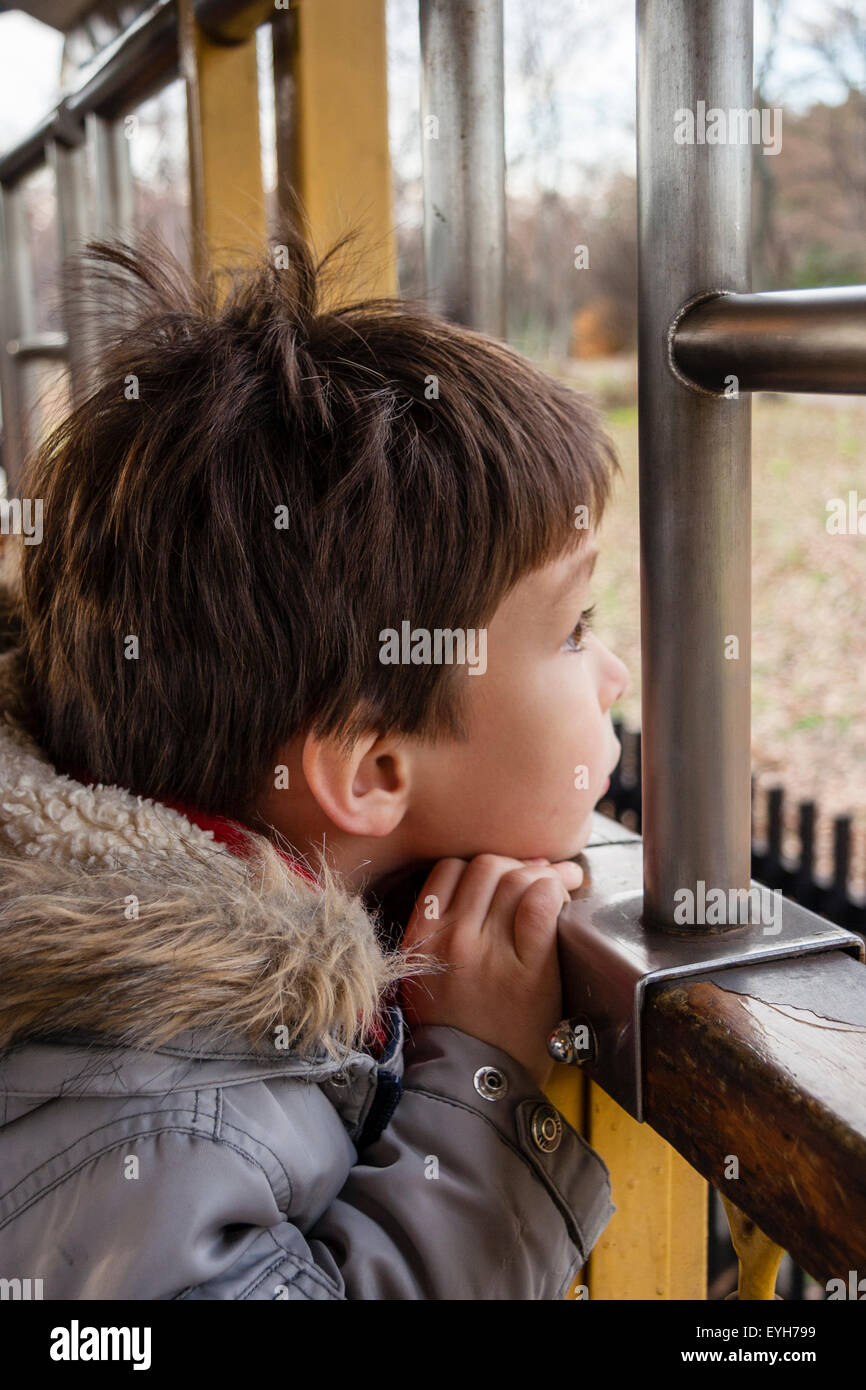 Boy Sitting By Open Window Of Old Type Of Train Looking Out Stock