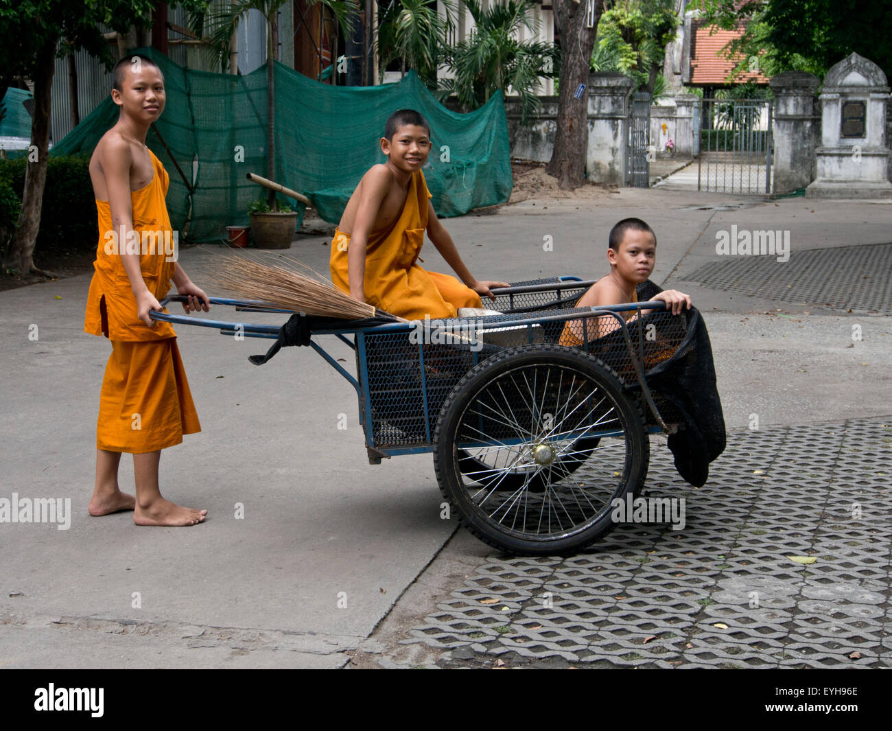 Young Buddhist novice monks with wheelbarrow doing cleaning service at a temple in Chiang Mai, Thailand Stock Photo