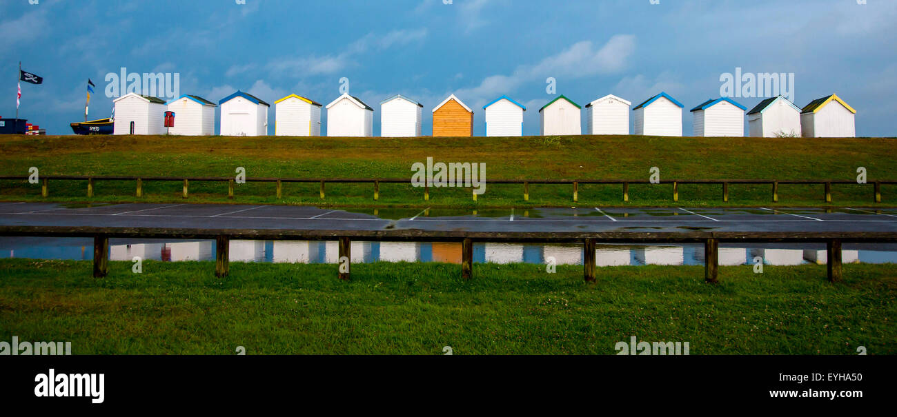 Beach huts at Lancing West Sussex under a stormy sky reflected in water