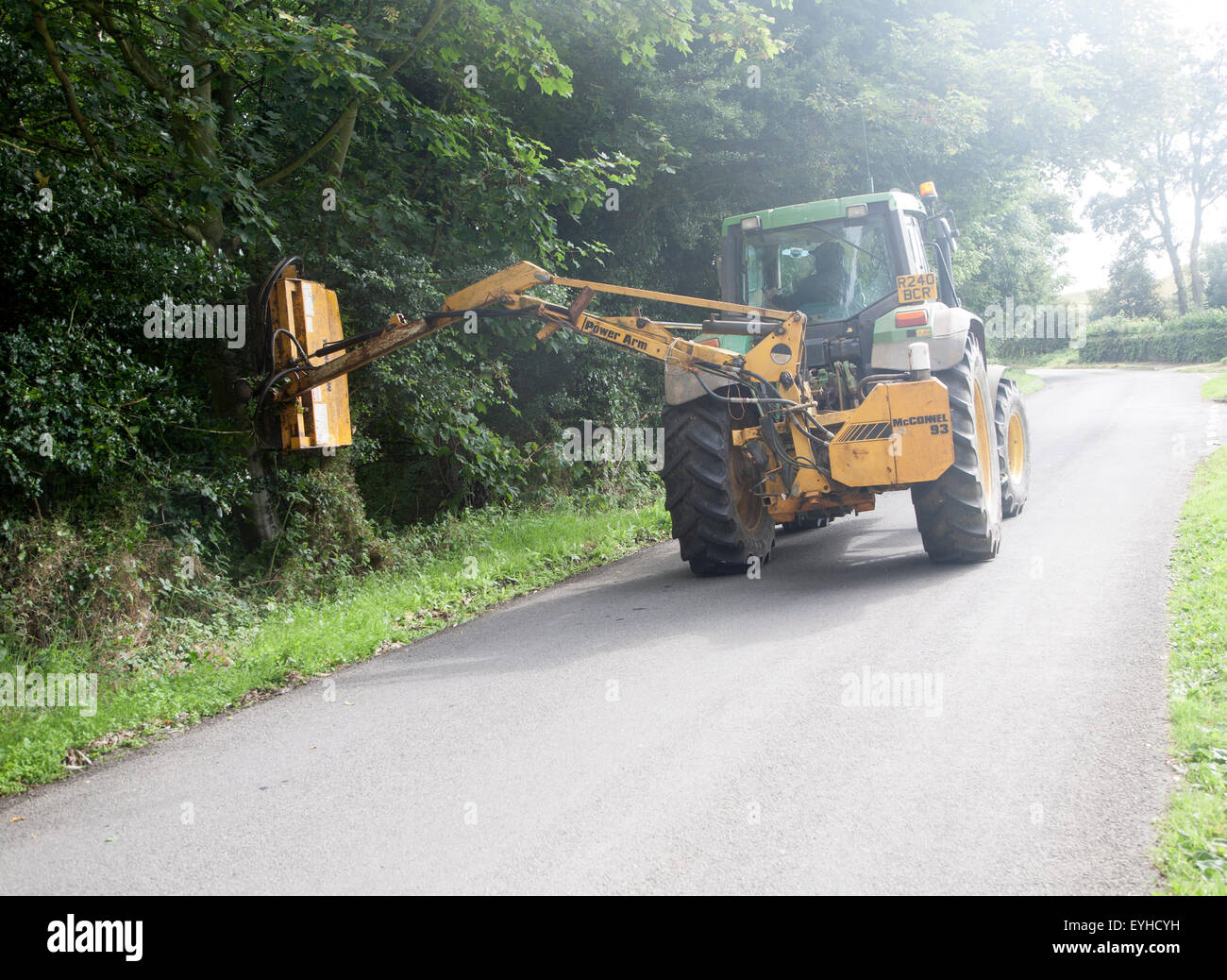 Tractor cutting back roadside vegetation hedge trimming hires stock