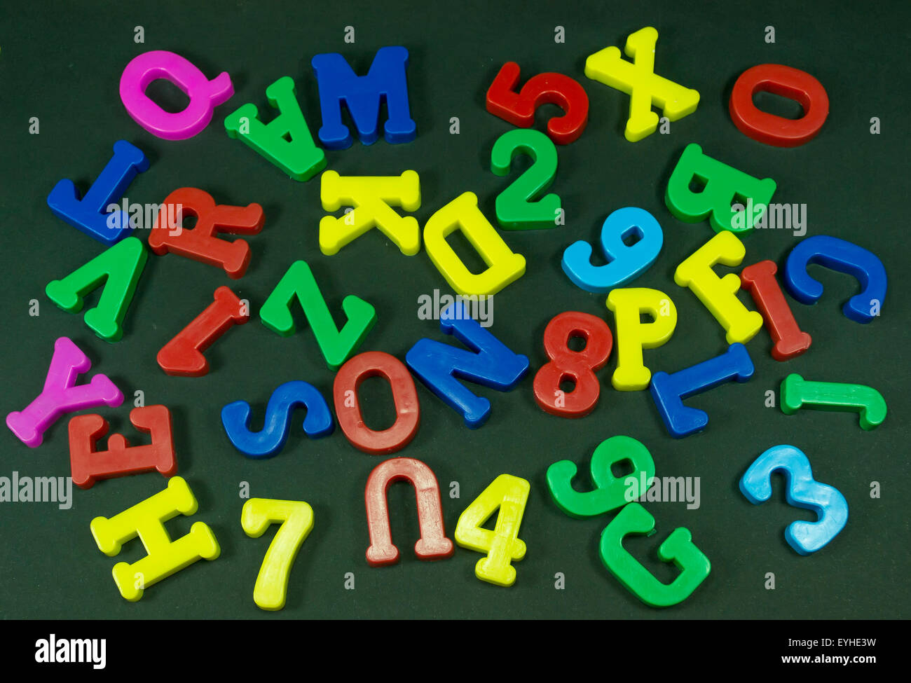 Plastic colored numbers and letters randomly placed on a black background Stock Photo