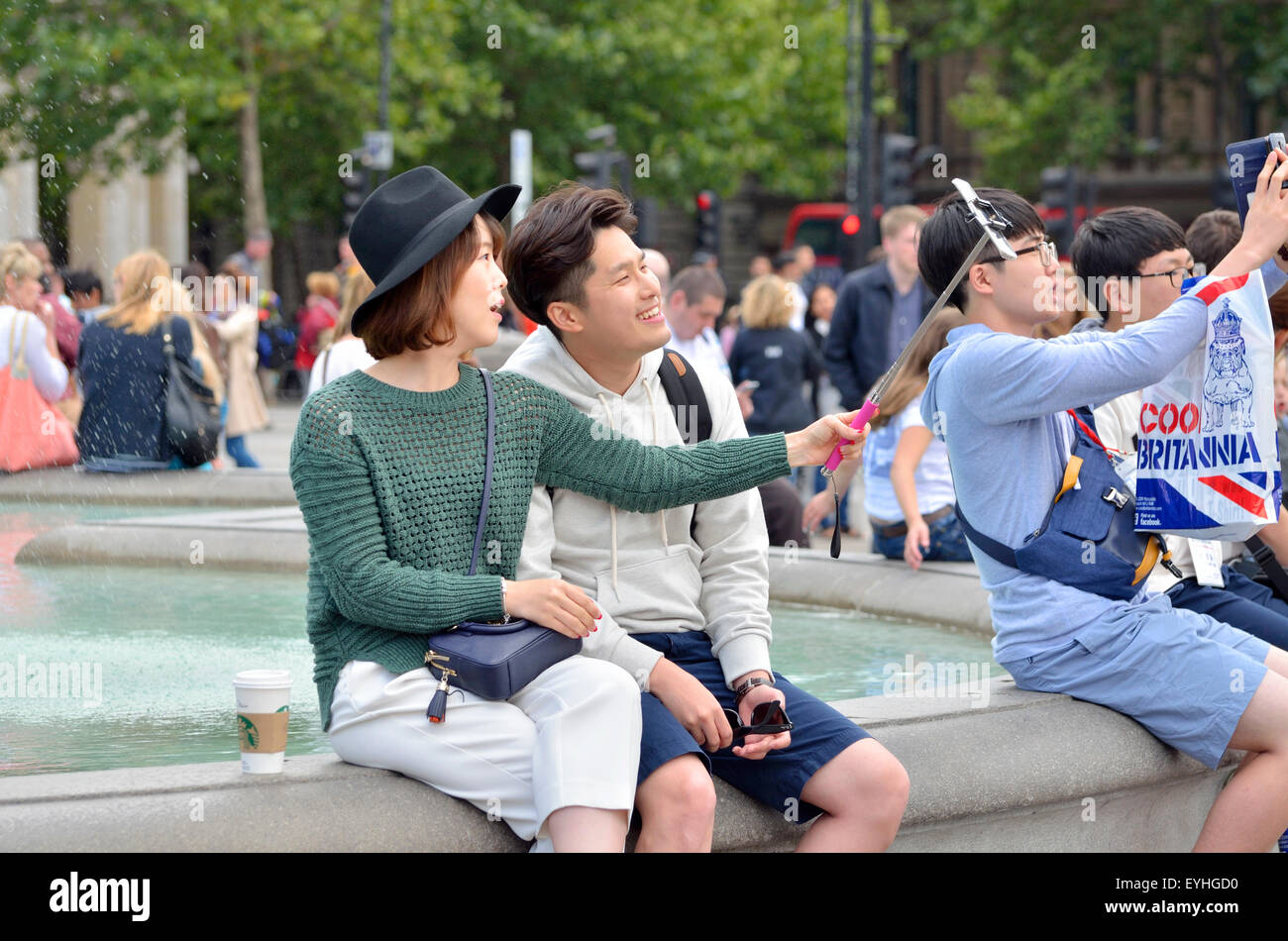 London, England, UK. Young Japanese couple in Trafalgar Square taking their photo with a selfie stick Stock Photo