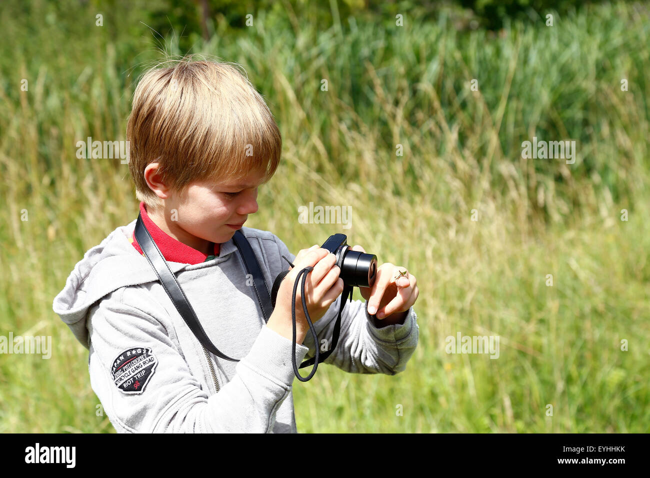 Young boy takes a picture of a grasshopper on his finger Stock Photo