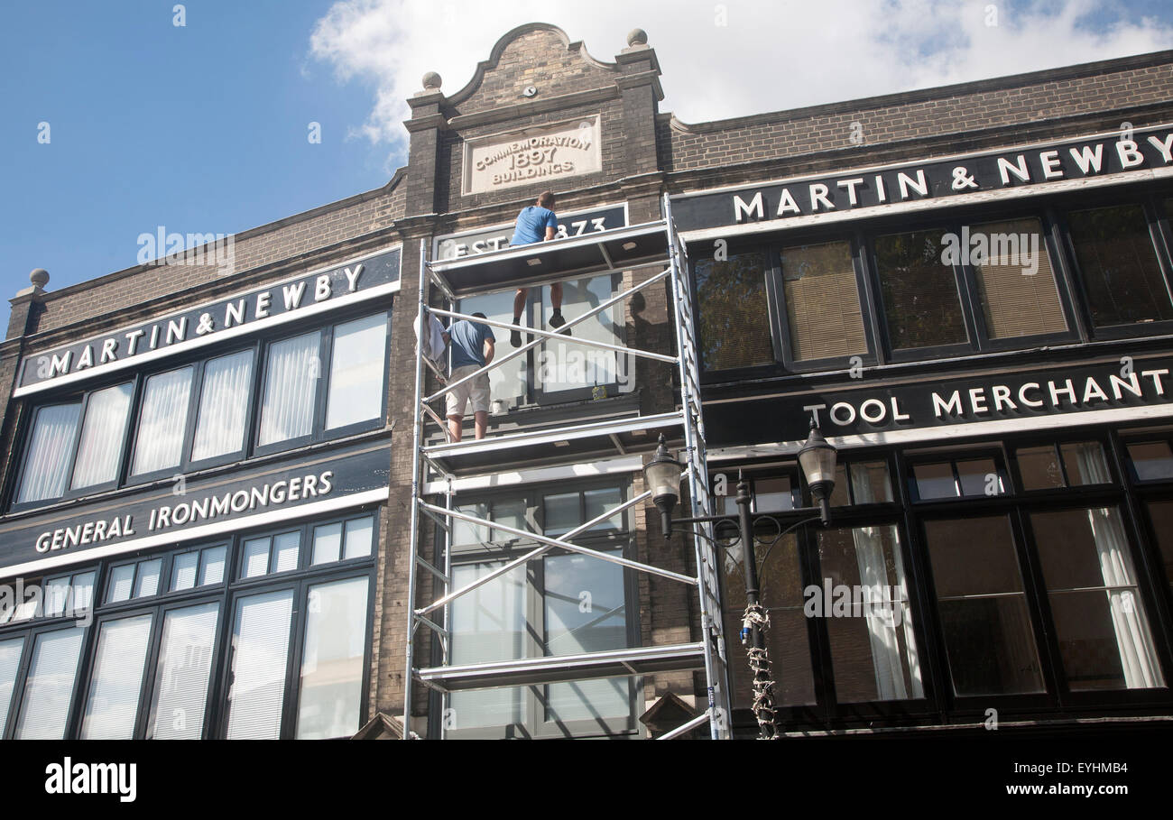 Painters working on scaffolding painting the Martin and Newby ironmongers shop building in Ipswich, Suffolk, England, UK Stock Photo