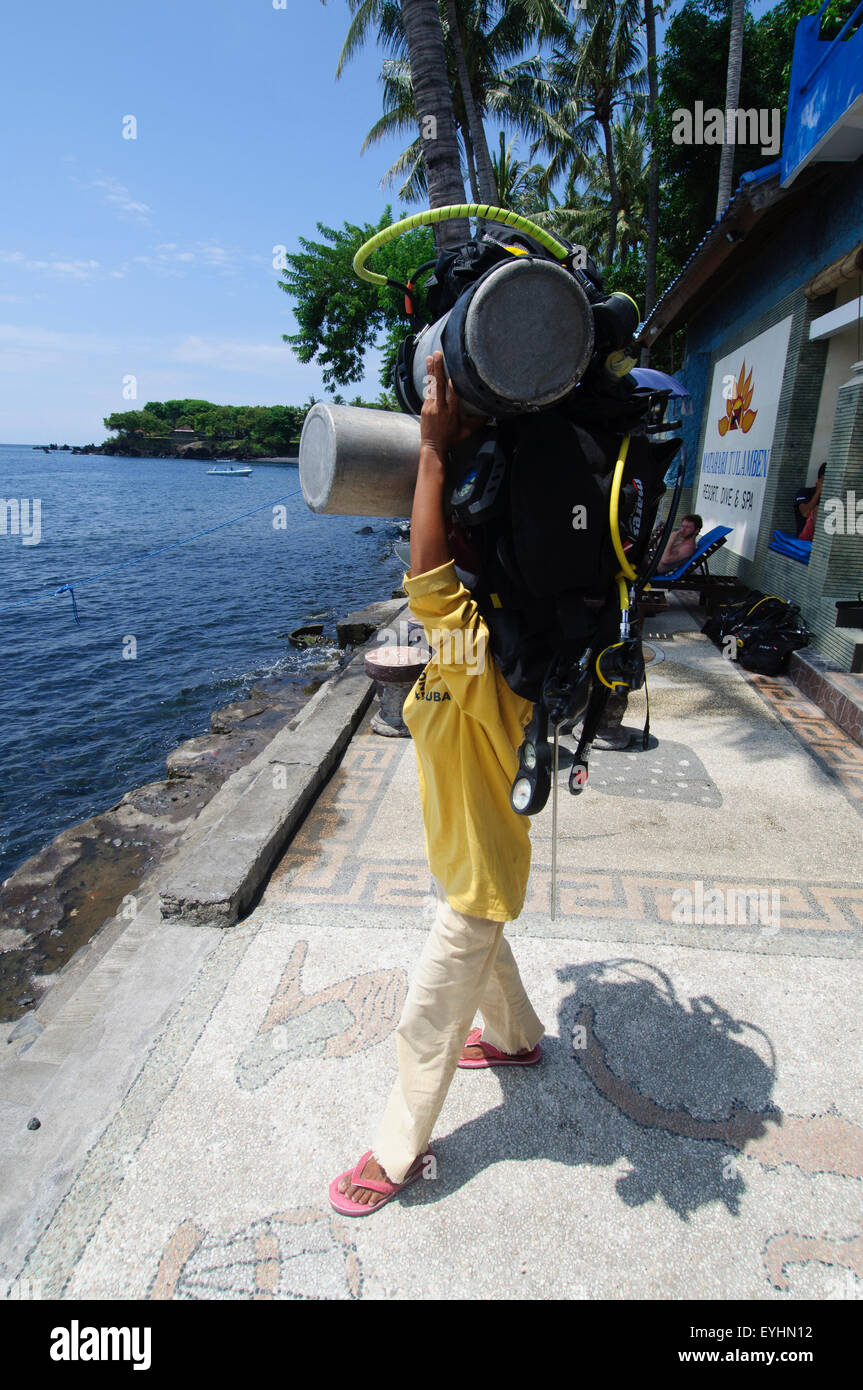 A female porter carries two fully loaded scuba tanks on her head, Tulamben, Bali, Indonesia (no MR) Stock Photo