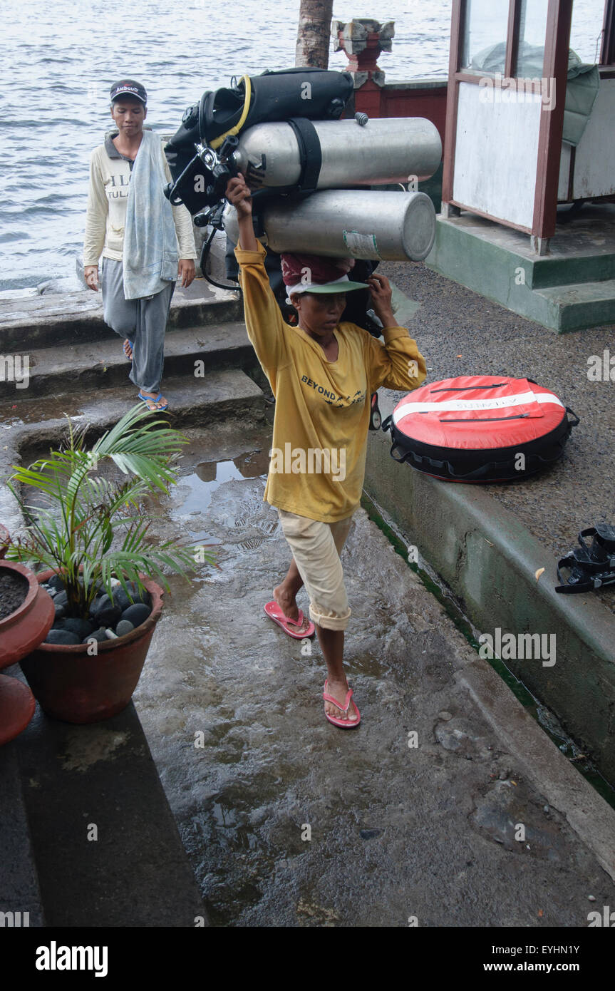 A female porter carries two fully loaded scuba tanks on her head, Tulamben, Bali, Indonesia (No MR) Stock Photo