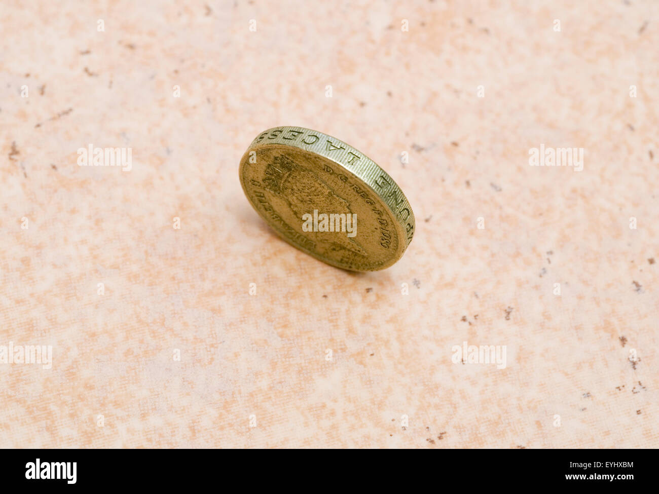 Single British Pound Coin Standing On Edge On The Floor Stock