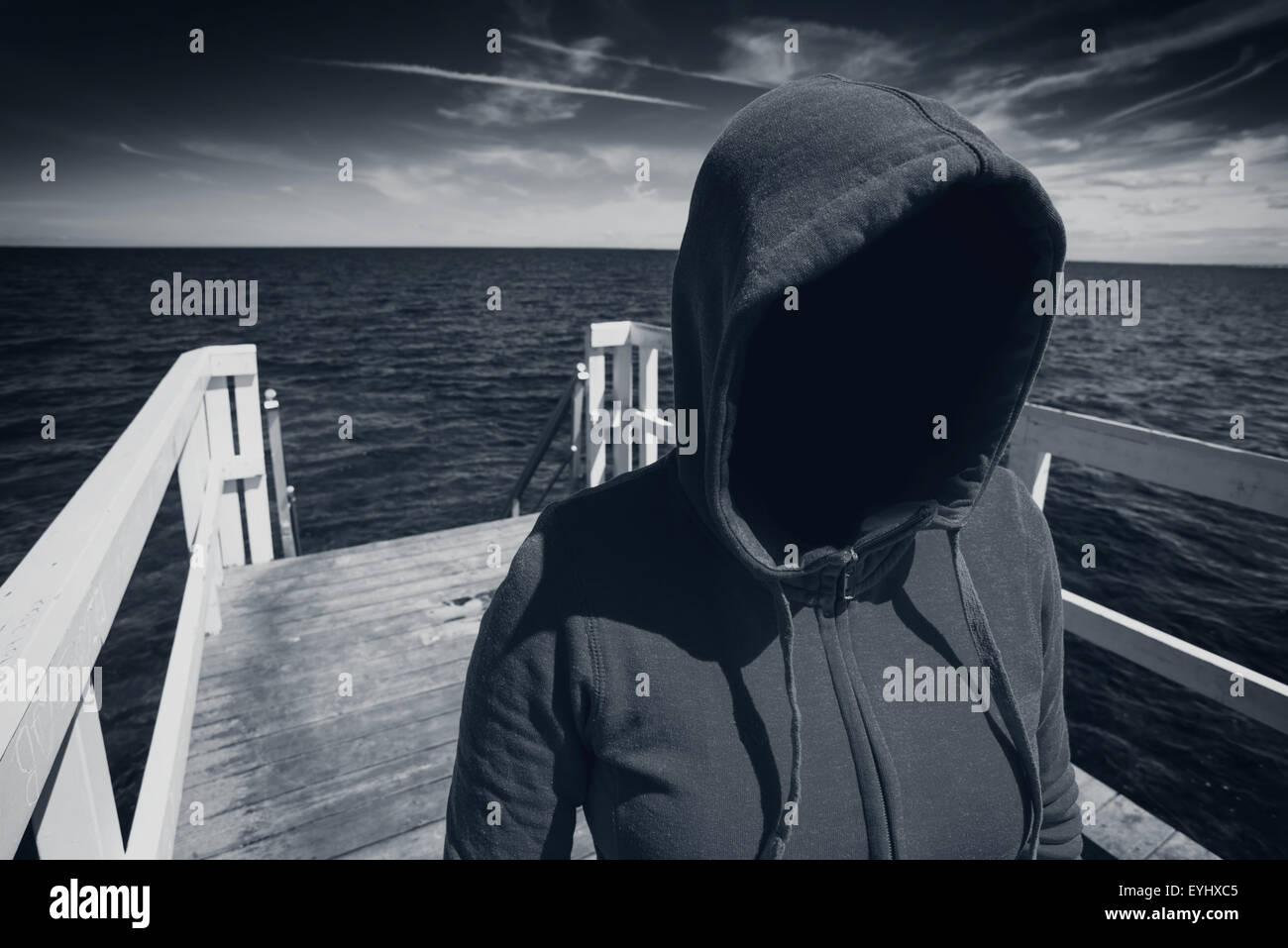Abduction Concept, Faceless Hooded Unrecognizable Woman at Ocean Pier, Unknown Spooky Female, Black and White Image Stock Photo