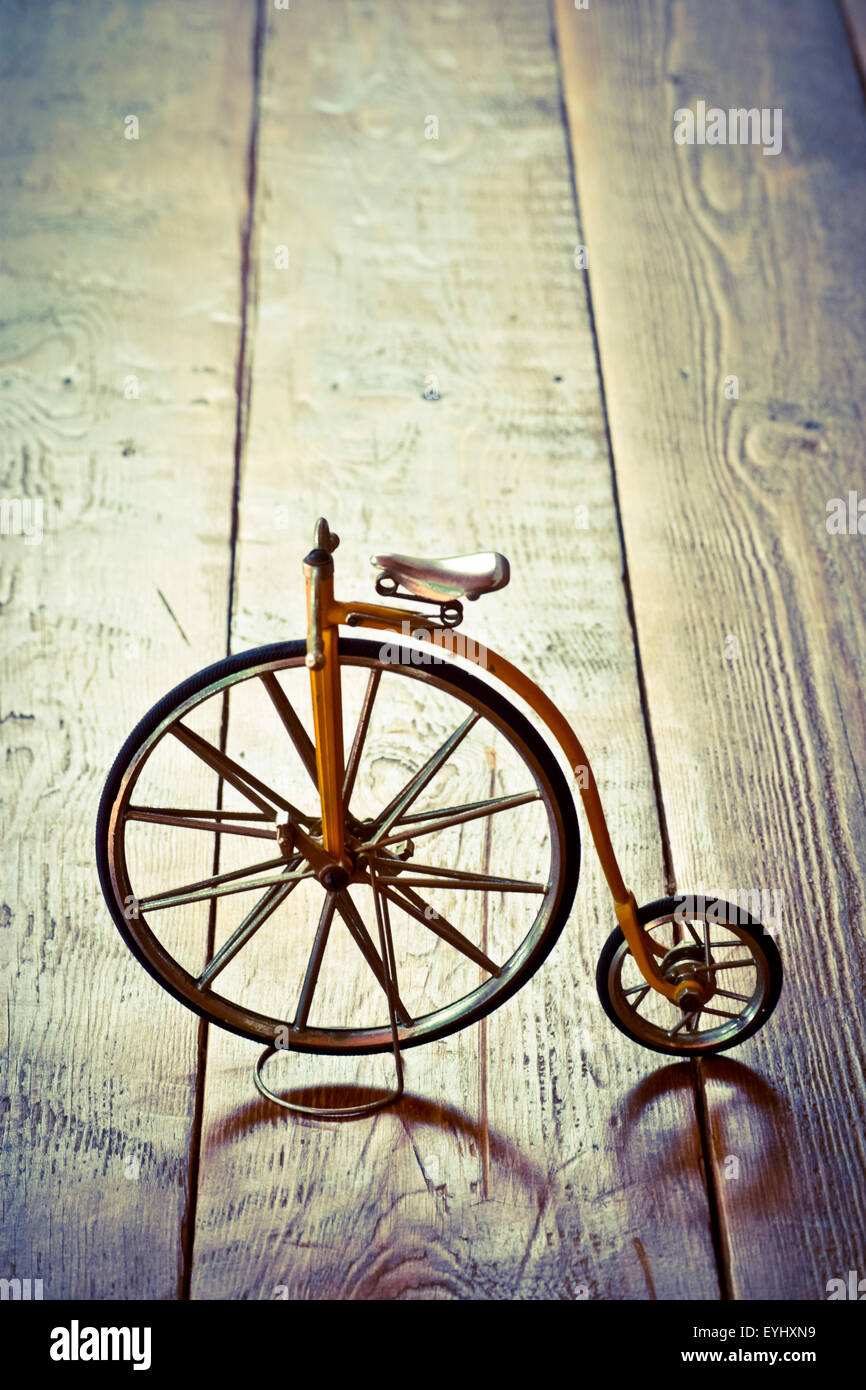 Old bicycle with big and small wheel on a wooden surface. Stock Photo