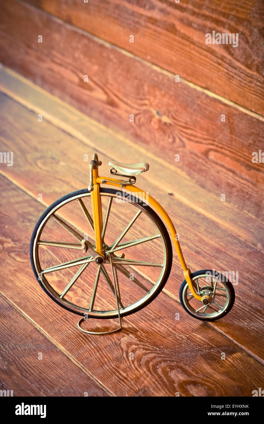 Old bicycle with big and small wheel on a wooden surface. Stock Photo