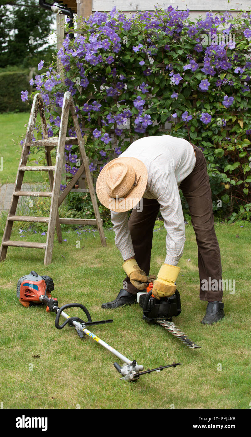 Gardener starting petrol hedge cutter before cutting a hedge Stock