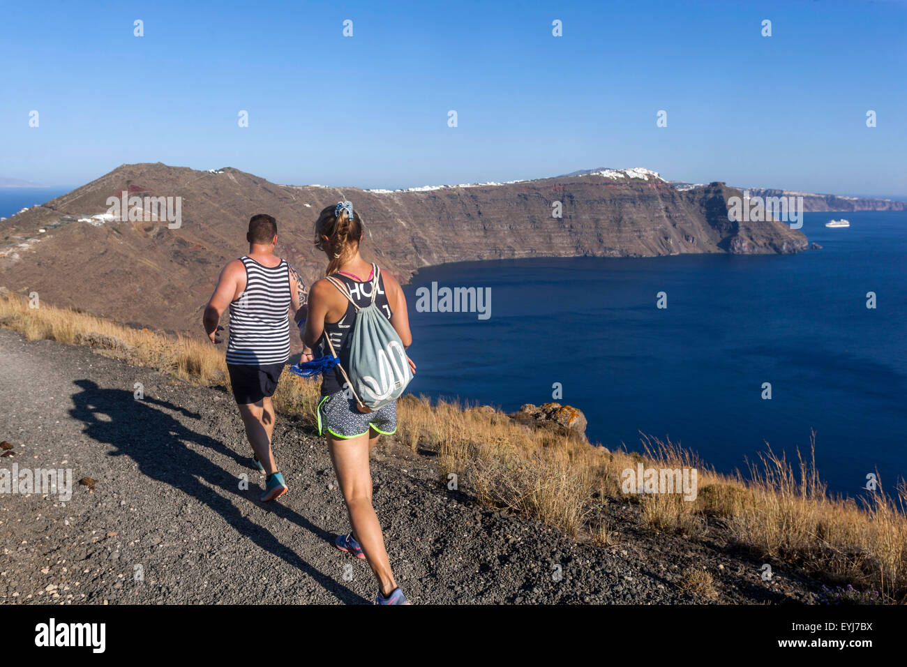 The road from Oia to Fira Santorini landscape couple hike, Caldera ridge path, Greek Islands hiking Greece countryside Europe people walking rear view Stock Photo