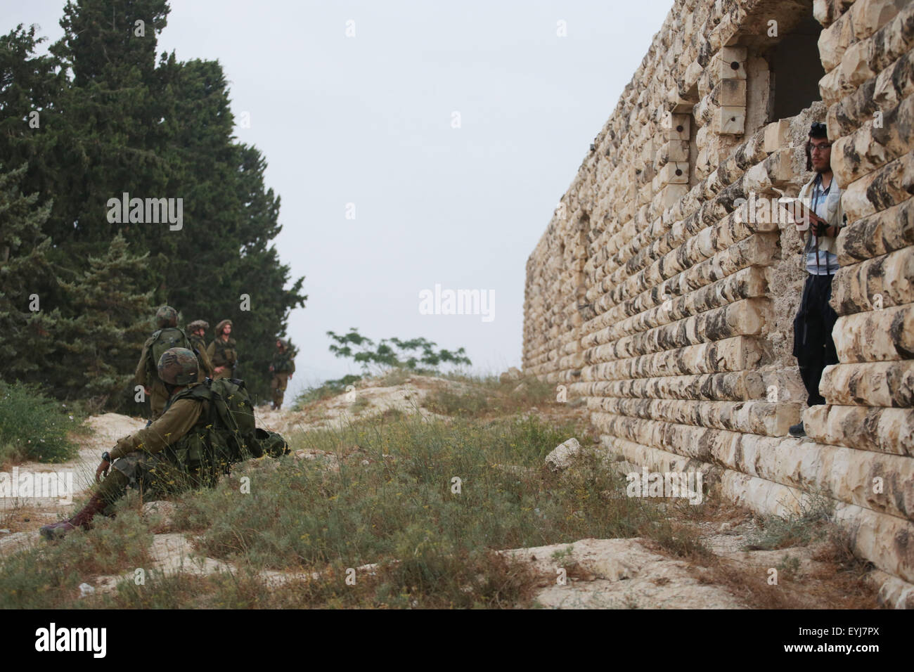 Jerusalem. 30th July, 2015. An Israeli Jewish settler prays while Israeli security forces guard in the settlement of the Sa-Nur in the northern West Bank, on July 30, 2015. Israeli security forces on Thursday evacuated about 200 settlers from the site of the former illegal settlement of the Sa-Nur in the northern West Bank, a military spokesperson said in a statement. Since Sa-Nur was evacuated as part of the 2005 Disengagement plan from Gaza, former Sa-Nur residents have made several attempts to rebuild their settlement. © JINI/Miri Tzachi/Xinhua/Alamy Live News Stock Photo