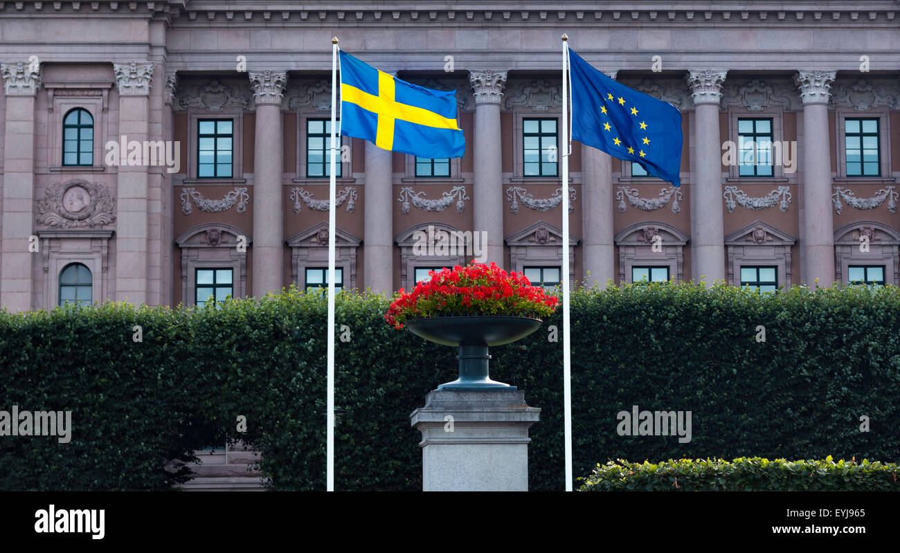 The Swedish Flag next to The Flag of the European Union with the Swedish Parliament (Riksdag) in the background. Stock Photo