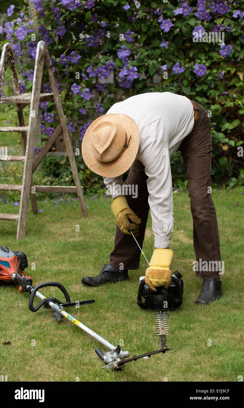 Gardener starting petrol hedge cutter before cutting a hedge Stock
