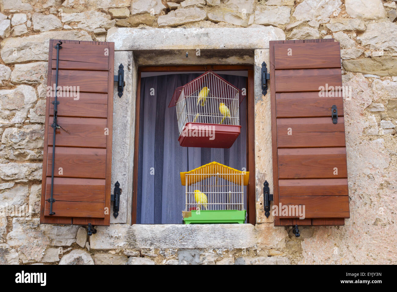 Beram, Istria, Croatia. An unspoilt medieval hilltop village. Caged canaries hang in a shuttered window Stock Photo
