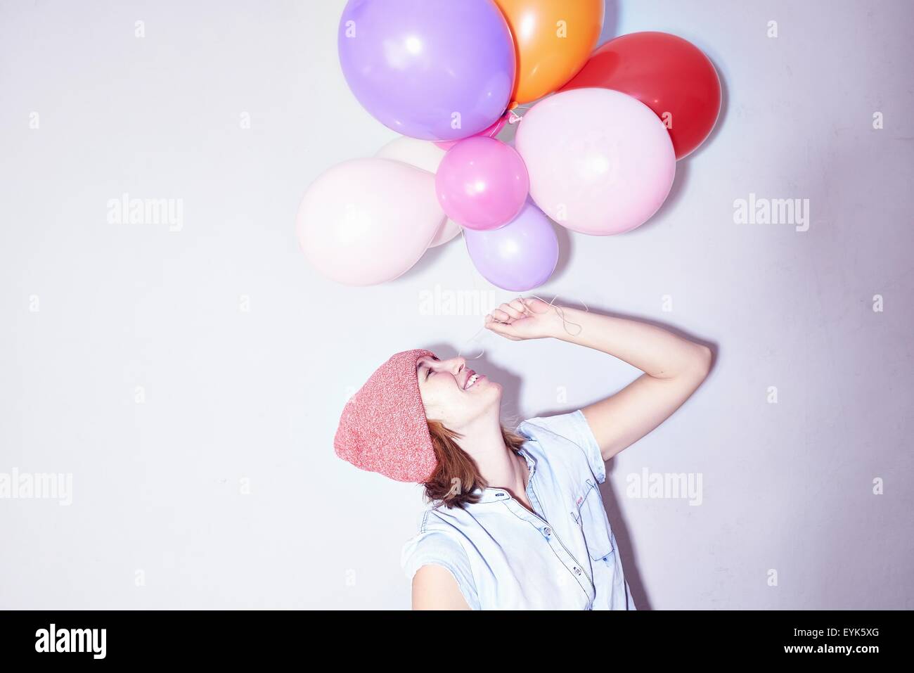 Studio shot of young woman holding up bunch of balloons Stock Photo