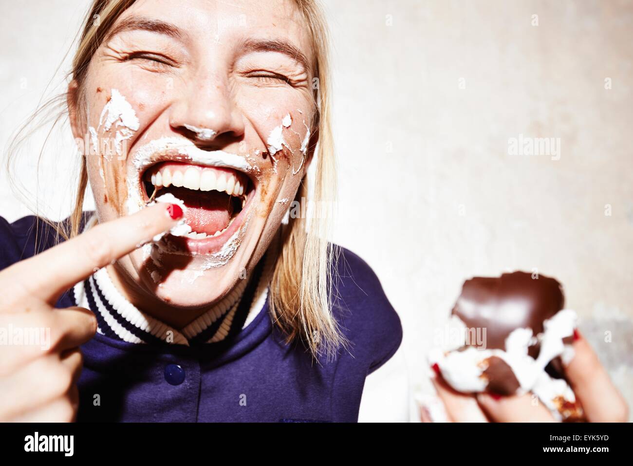 Close up studio shot of young woman with face covered in chocolate marshmallow Stock Photo