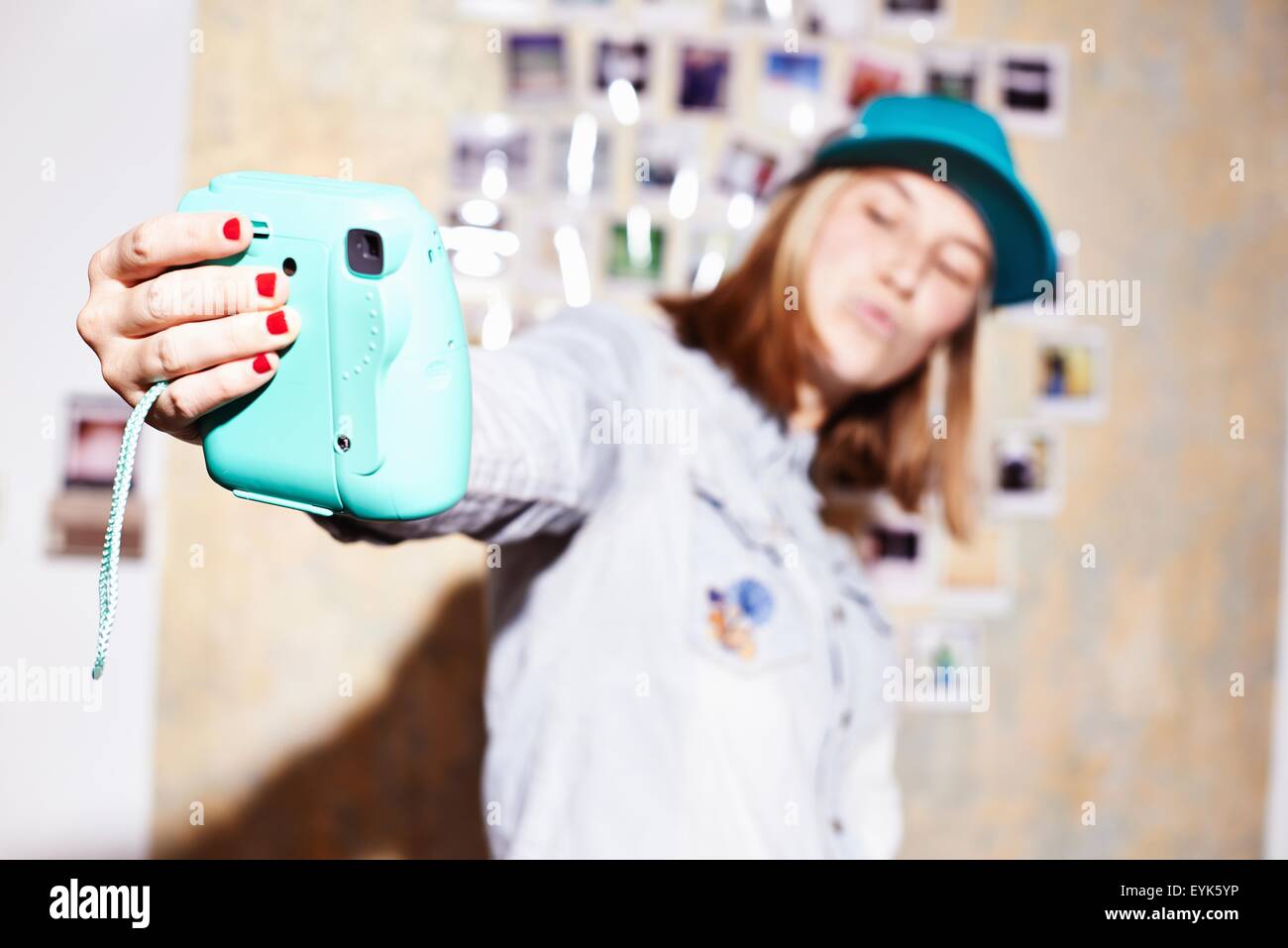 Young woman in front of photo wall posing for instant selfie Stock Photo