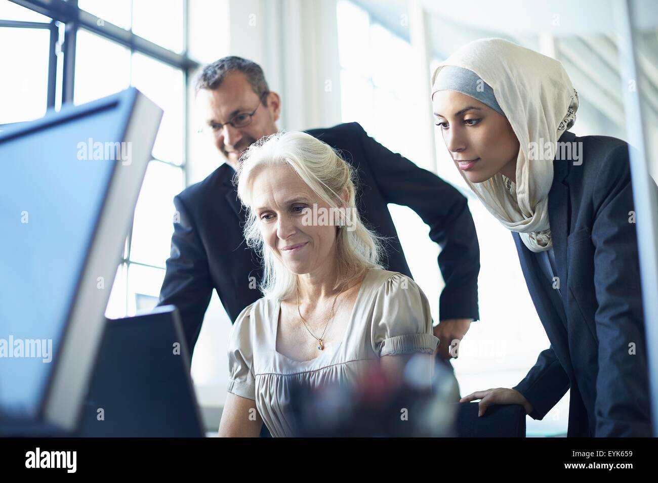 Business team looking at personal computer at office desk Stock Photo
