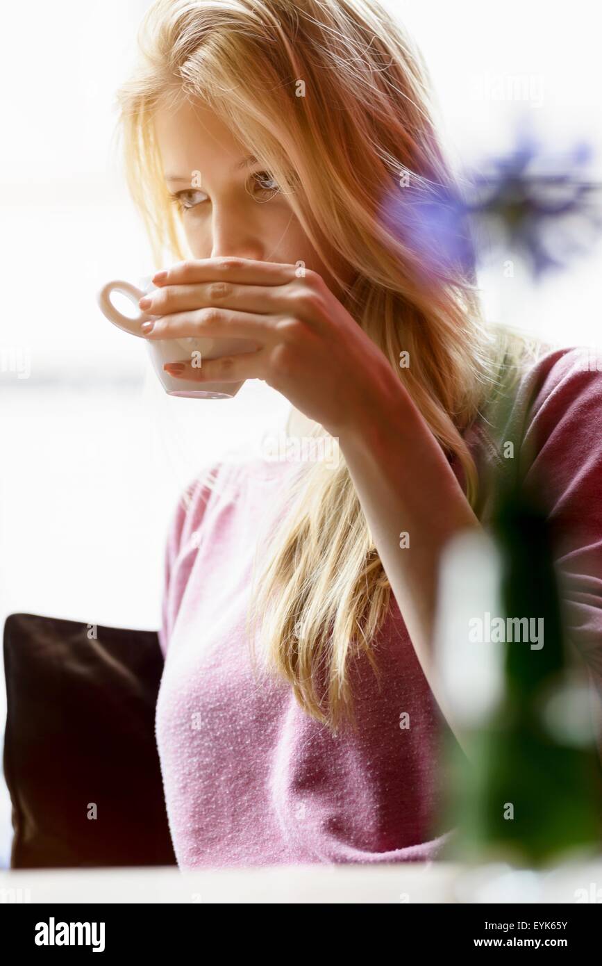 Young woman in cafe window seat drinking coffee Stock Photo