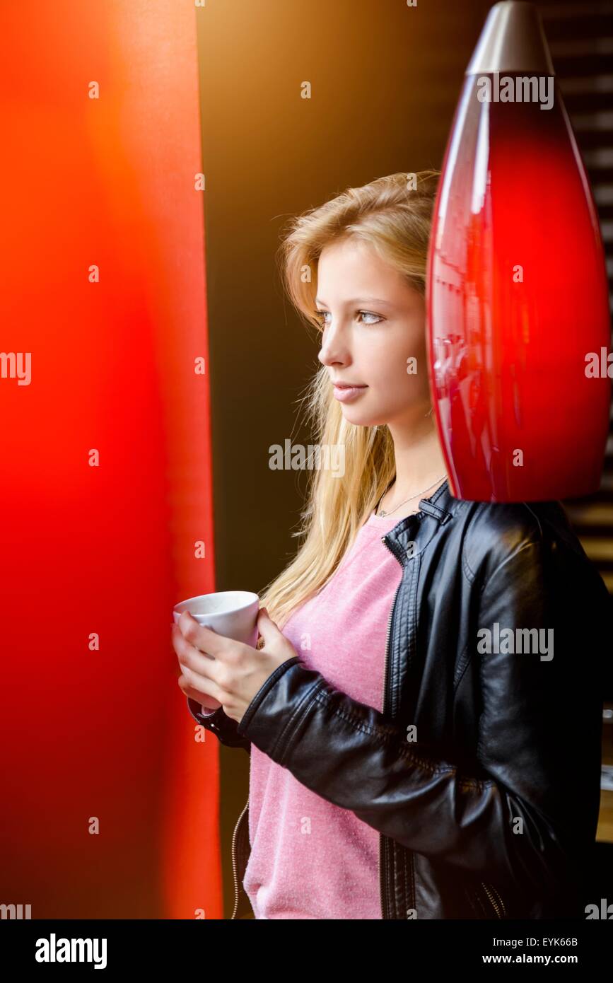 Portrait of young woman drinking coffee and gazing in cafe Stock Photo
