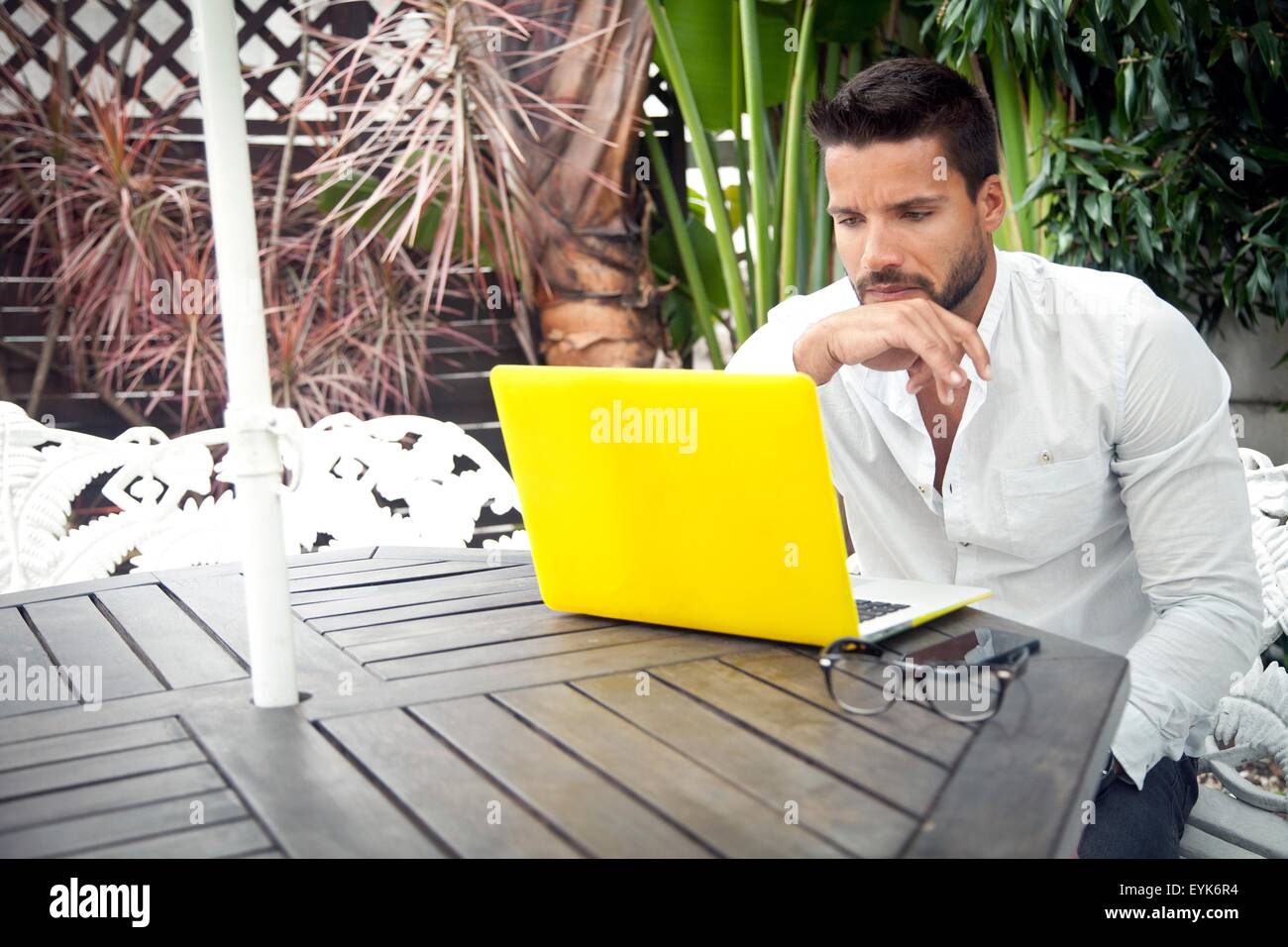 Man using laptop on patio Stock Photo