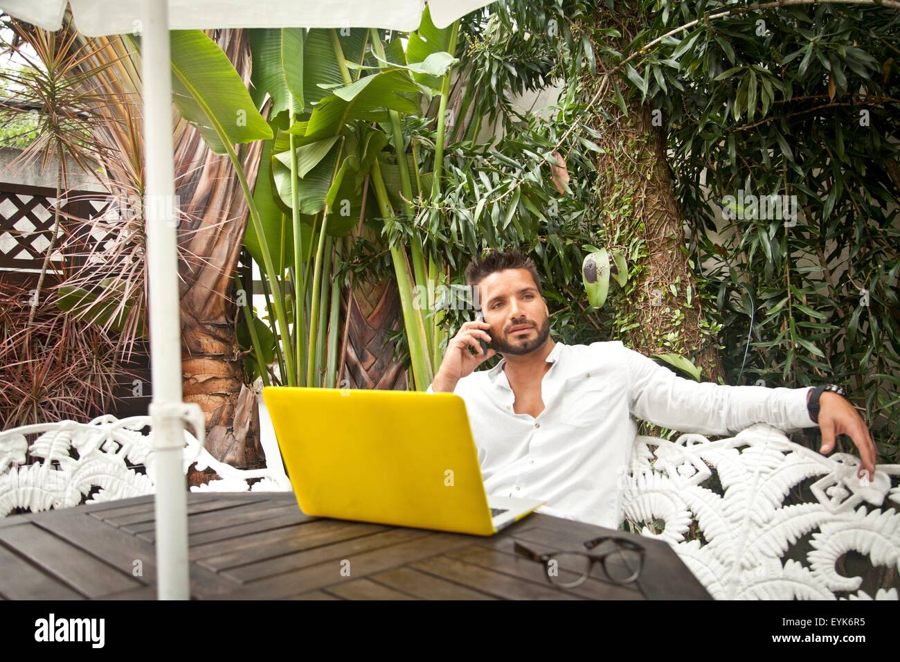Man using laptop on patio Stock Photo