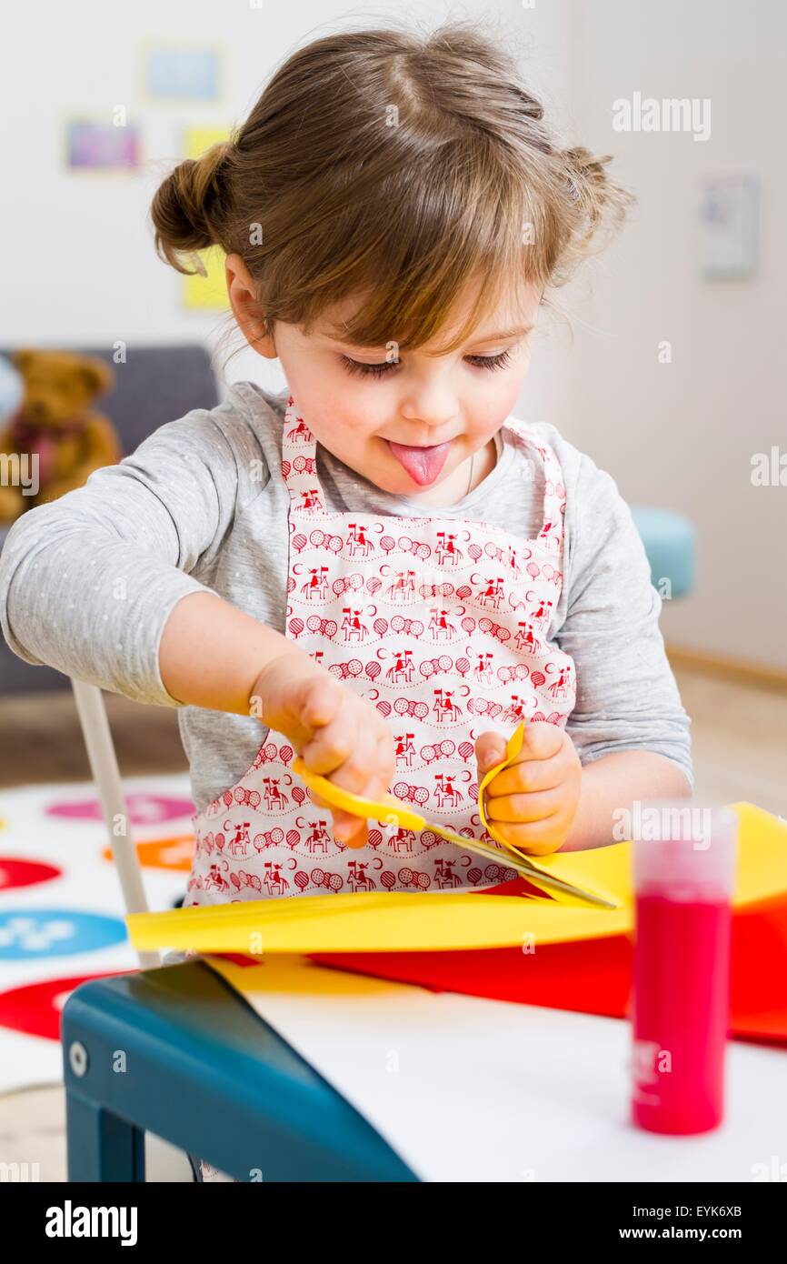Girl cutting coloured card at home Stock Photo