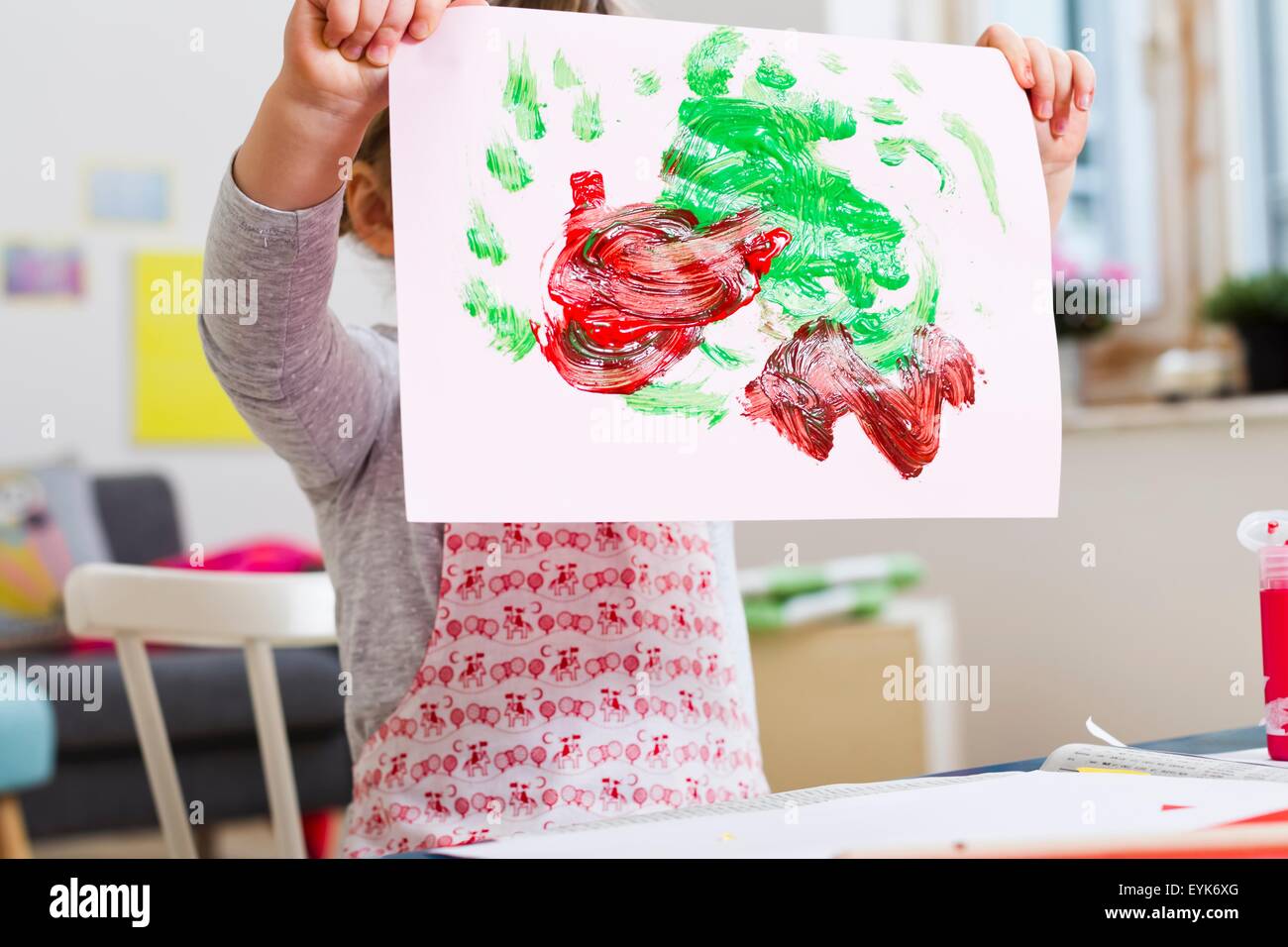 Girl holding up painting at home Stock Photo