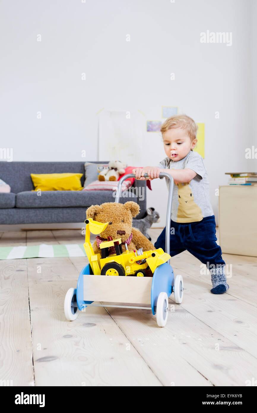 Boy pushing cart of toys at home Stock Photo Alamy