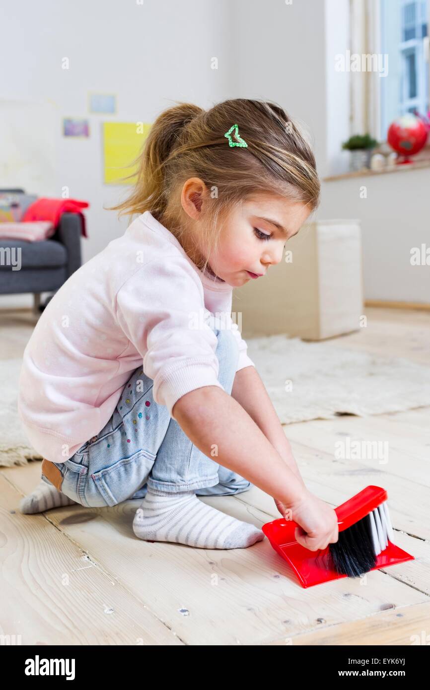 Girl sweeping floor with brush at home Stock Photo
