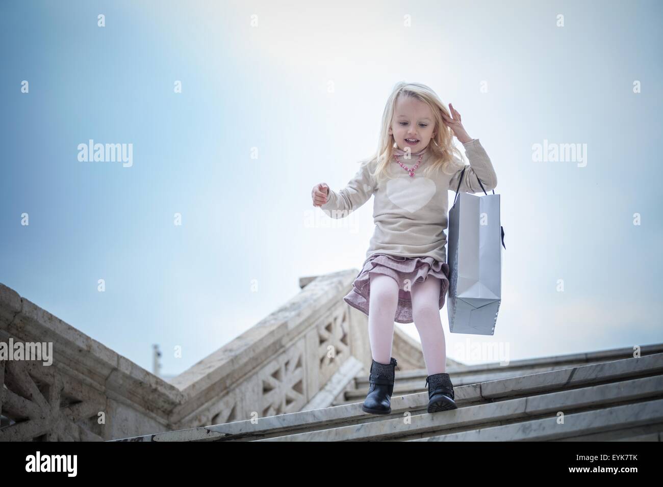 Young girl running down stairway carrying shopping bag, Cagliari, Sardinia, Italy Stock Photo